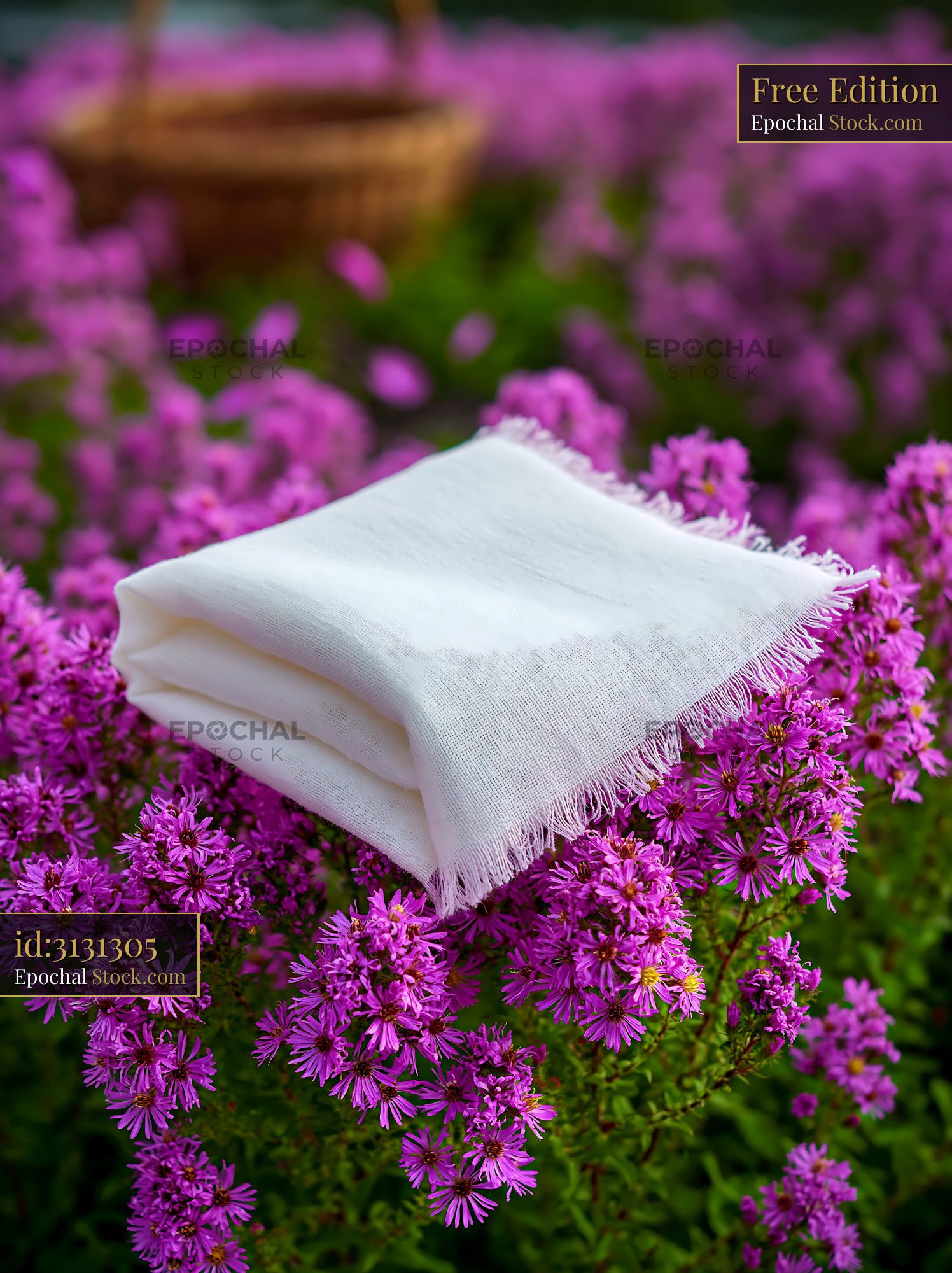 Folded white linen napkin resting on purple wildflowers in a field - stock photo