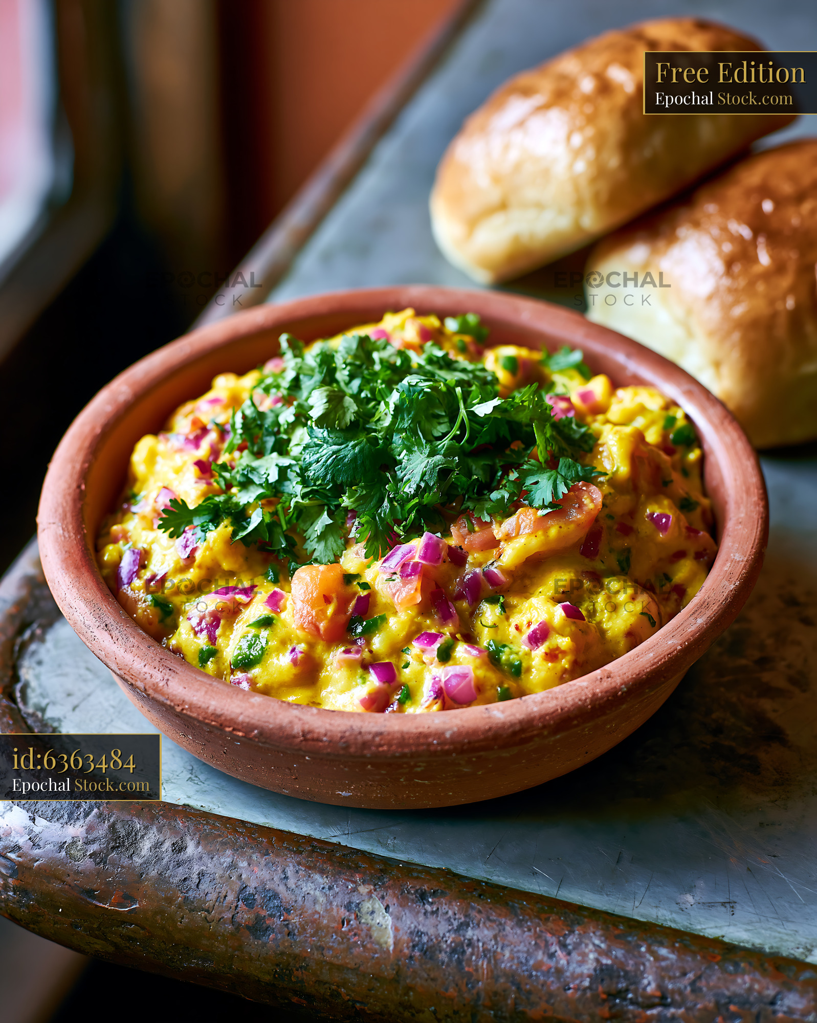 Akuri egg food in clay bowl with fresh coriander and pav buns - stock photo