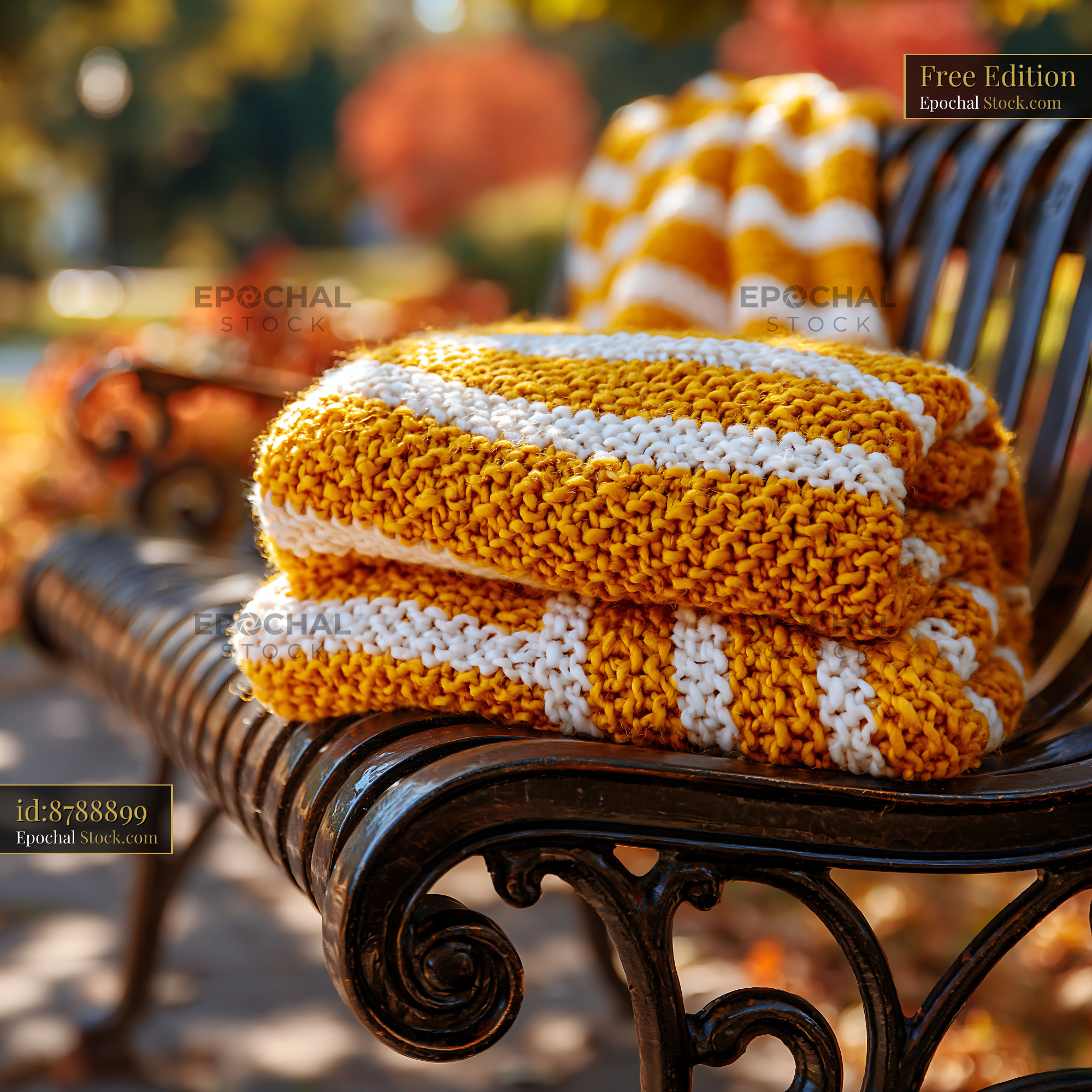 Yellow and white striped throw on bench in a sunny autumn park - stock photo