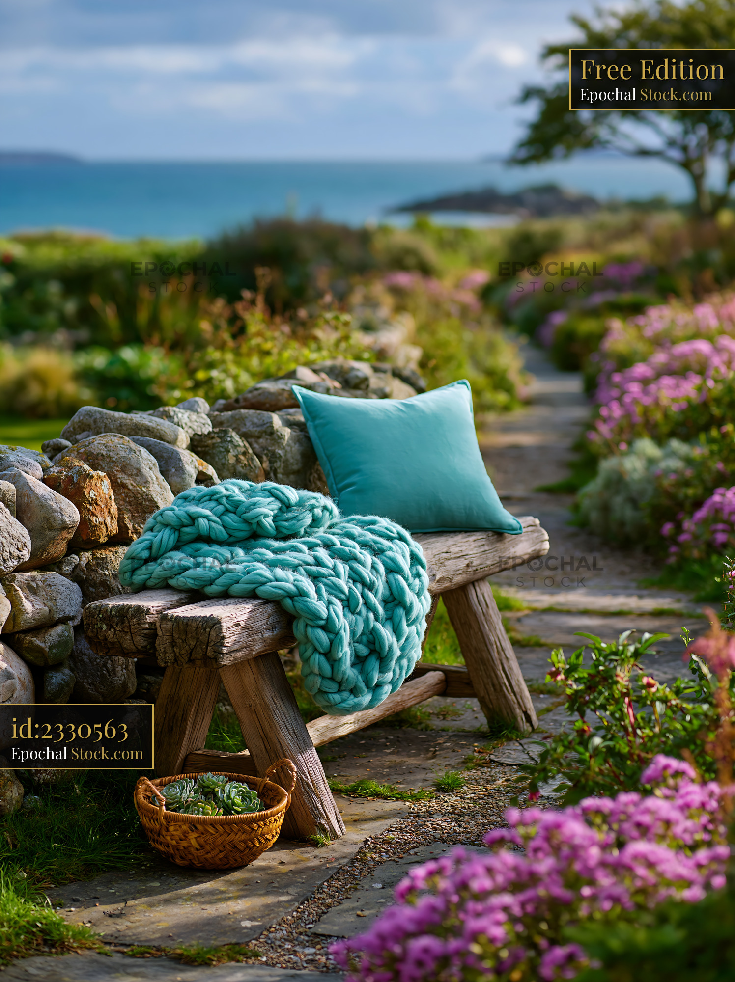 Chunky teal blanket and pillow on rustic wooden bench by the sea - stock photo