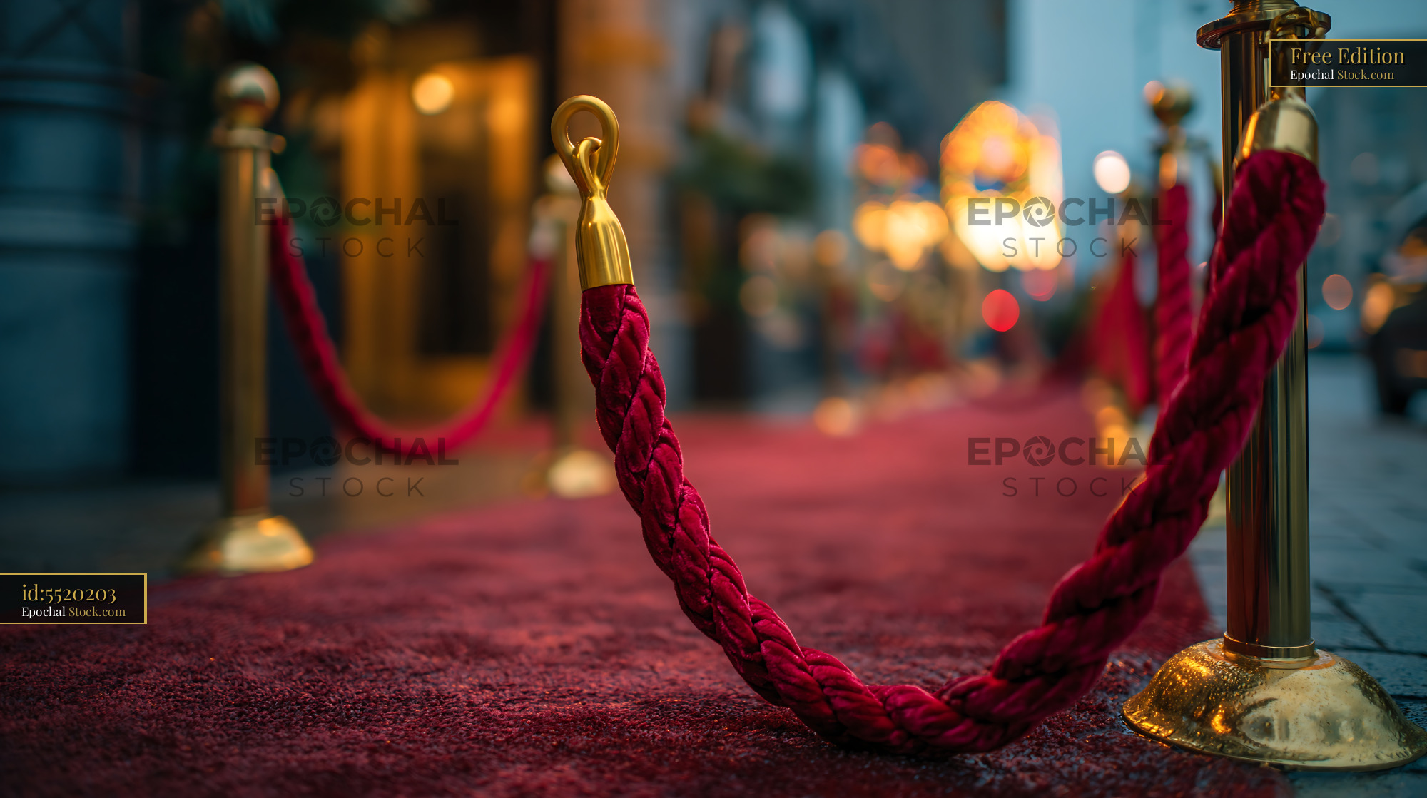 Red carpet with gold stanchions at a cinema entrance at night - stock photo