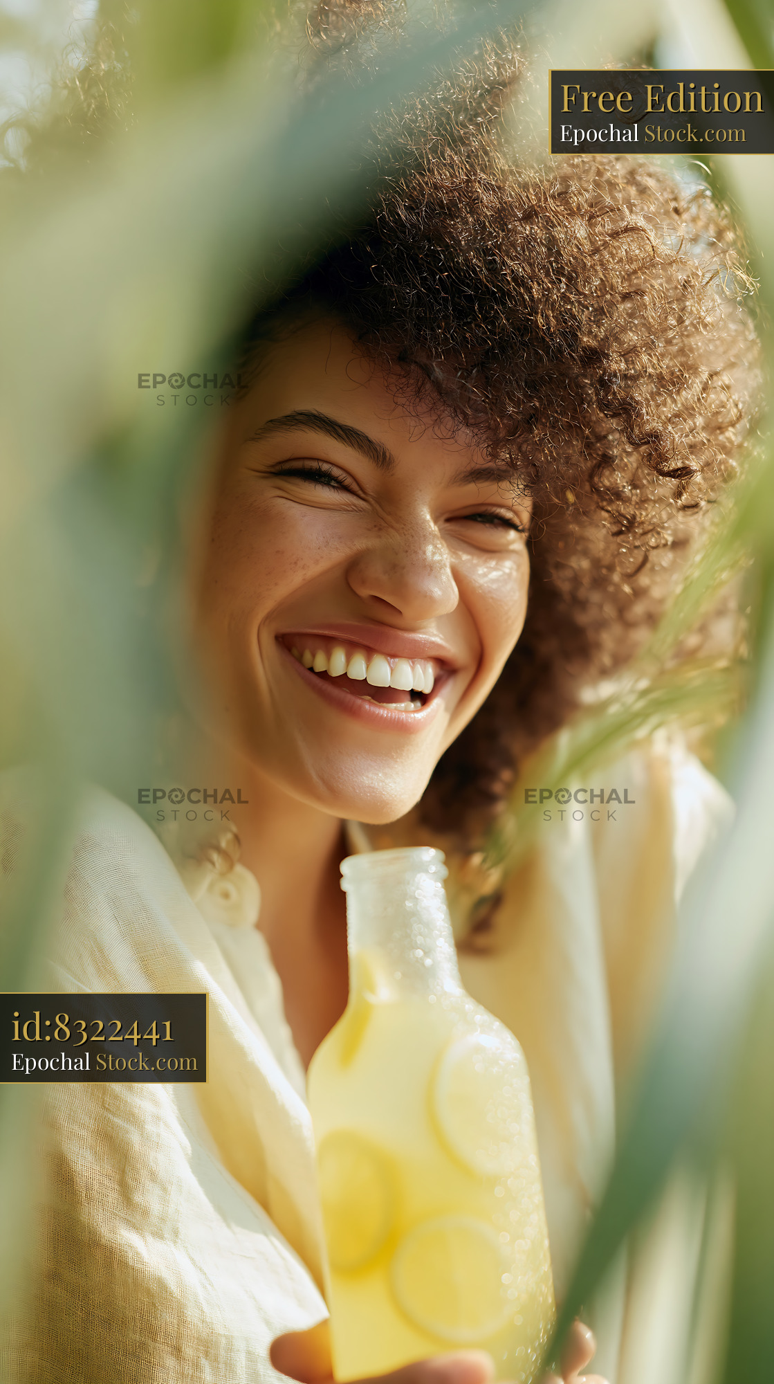 Young woman with curly hair laughing while holding a fresh lemonade - stock photo