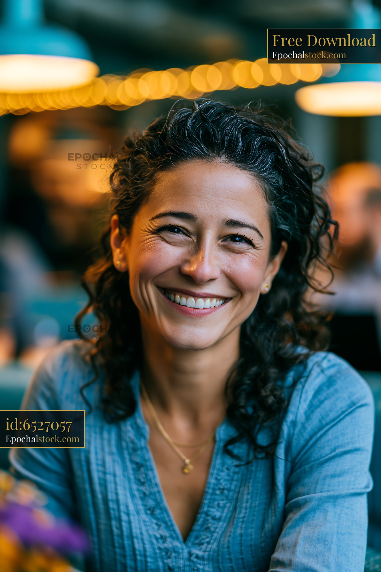 Watermarked full-resolution preview of Smiling woman with curly hair sitting in a cafe