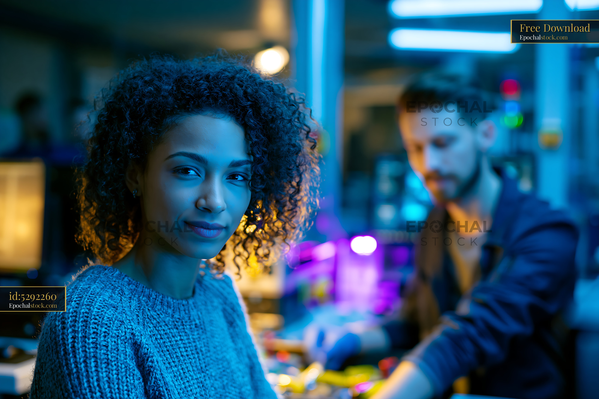 Watermarked full-resolution preview of Young woman looks at camera while man works in background
