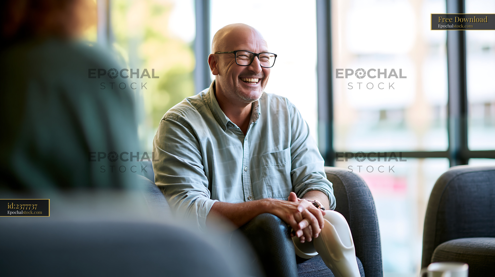 Watermarked full-resolution preview of Smiling man sitting indoors while talking to a friend