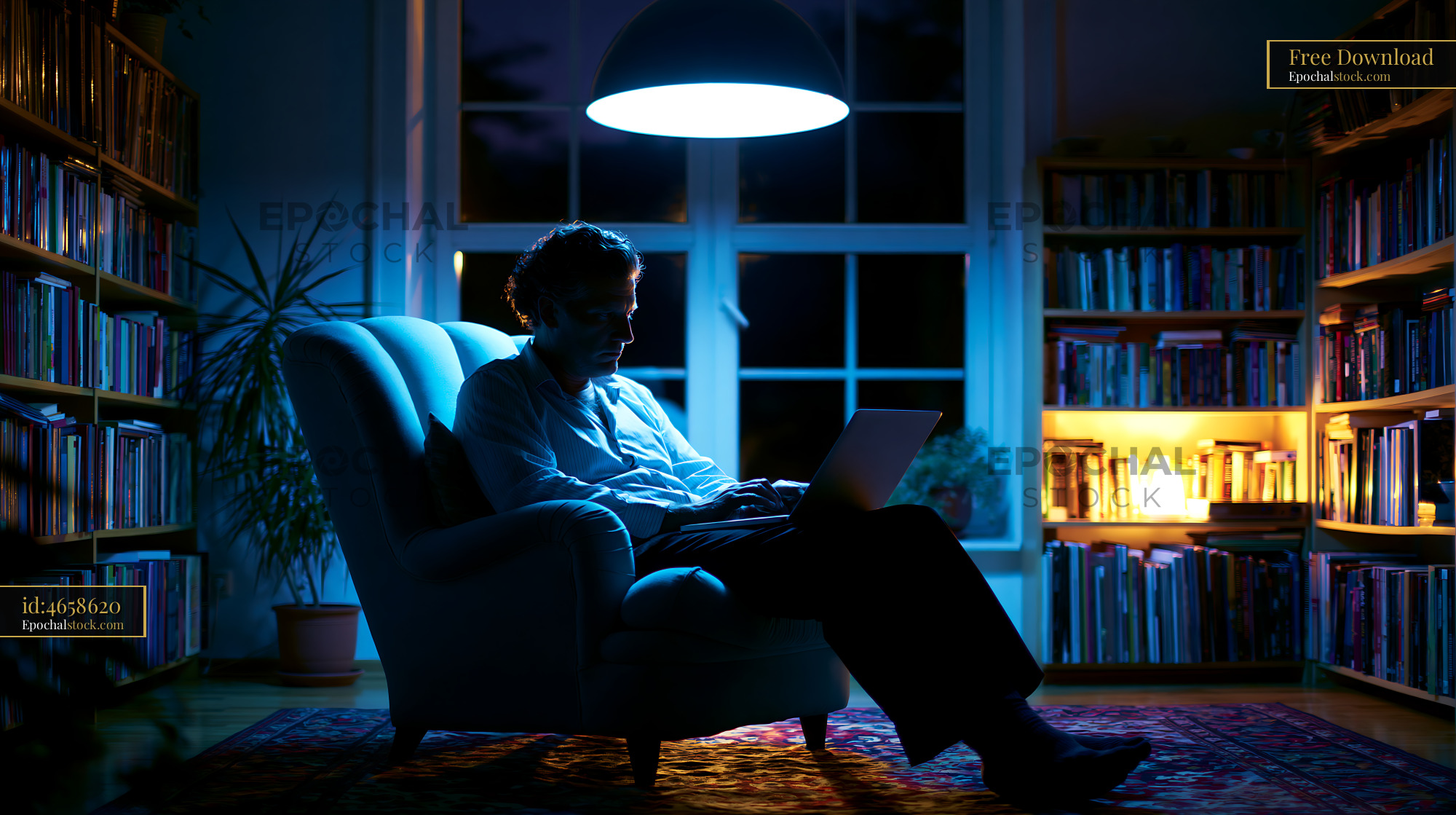 Watermarked full-resolution preview of Person sitting in a chair working on laptop in dimly lit room