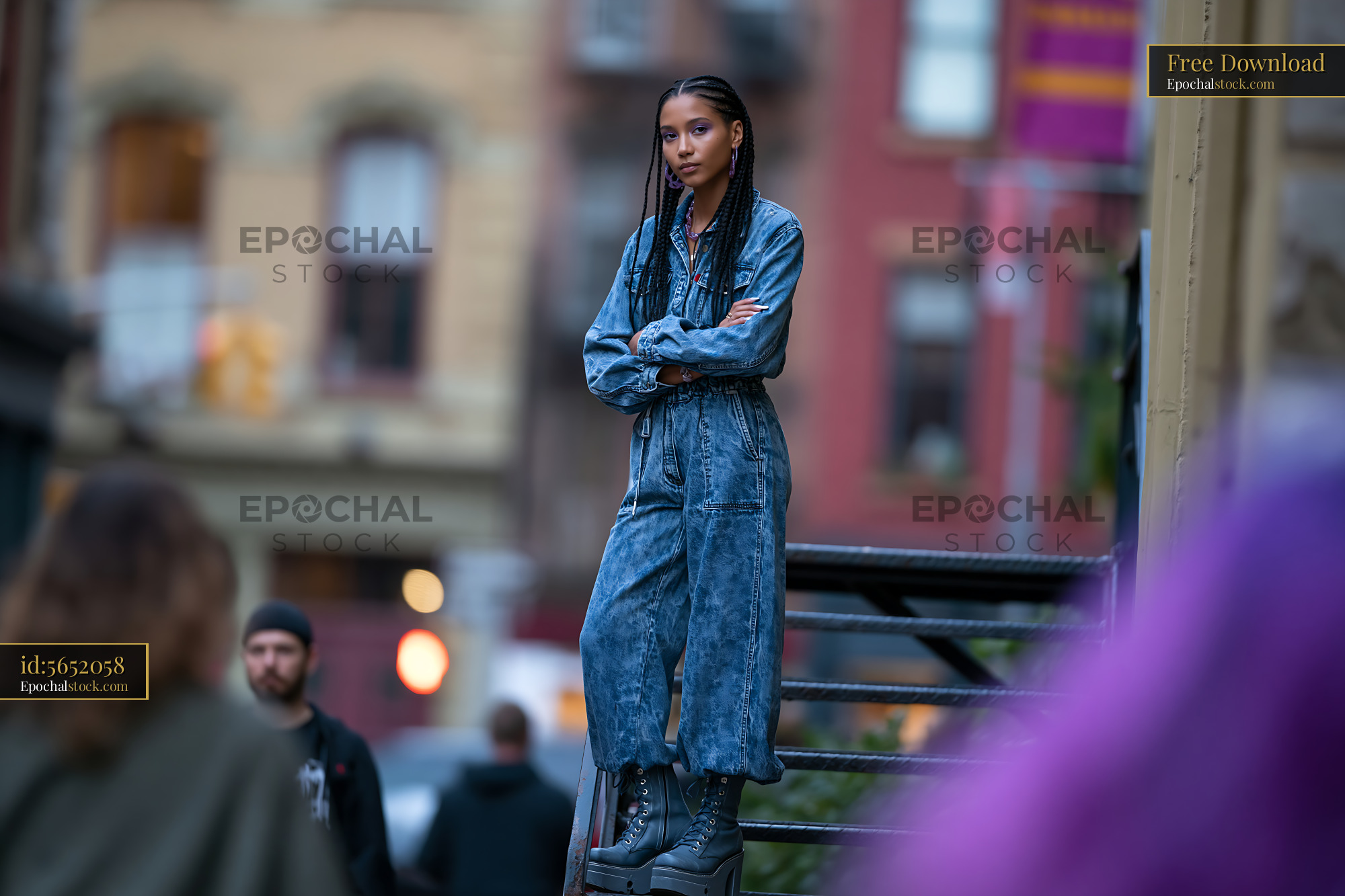 Watermarked full-resolution preview of Young woman in denim jumpsuit stands on stairs in urban area