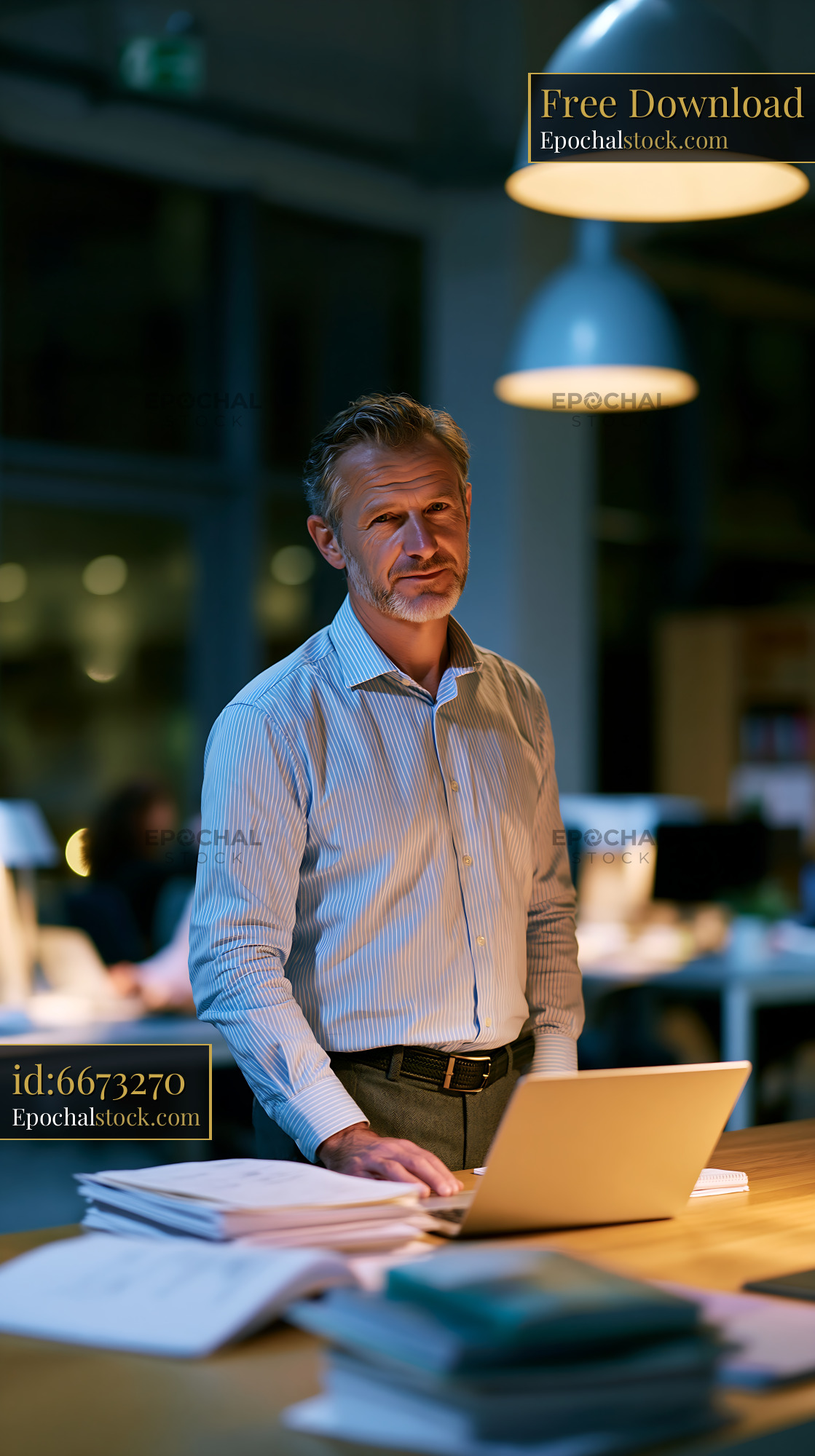 Watermarked full-resolution preview of Man working at a laptop in an office during evening hours