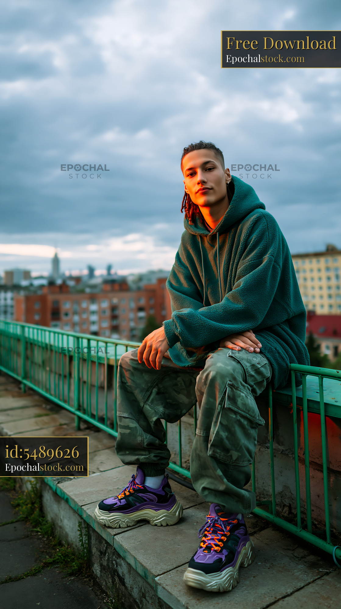 Watermarked full-resolution preview of Person sitting on a green railing with a city view