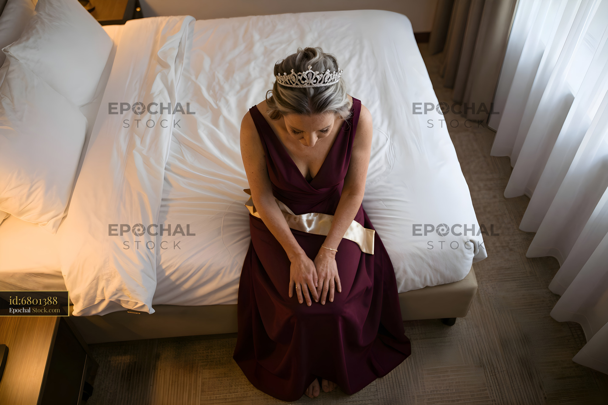 Woman in gown sitting on bed with crown Premium Stock Image