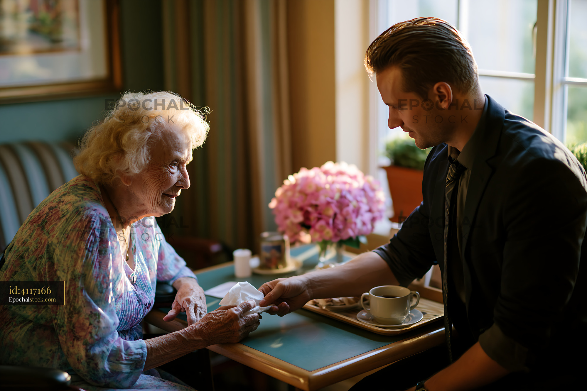 Watermarked full-resolution preview of Man serving tissue to elderly woman in cozy indoor setting