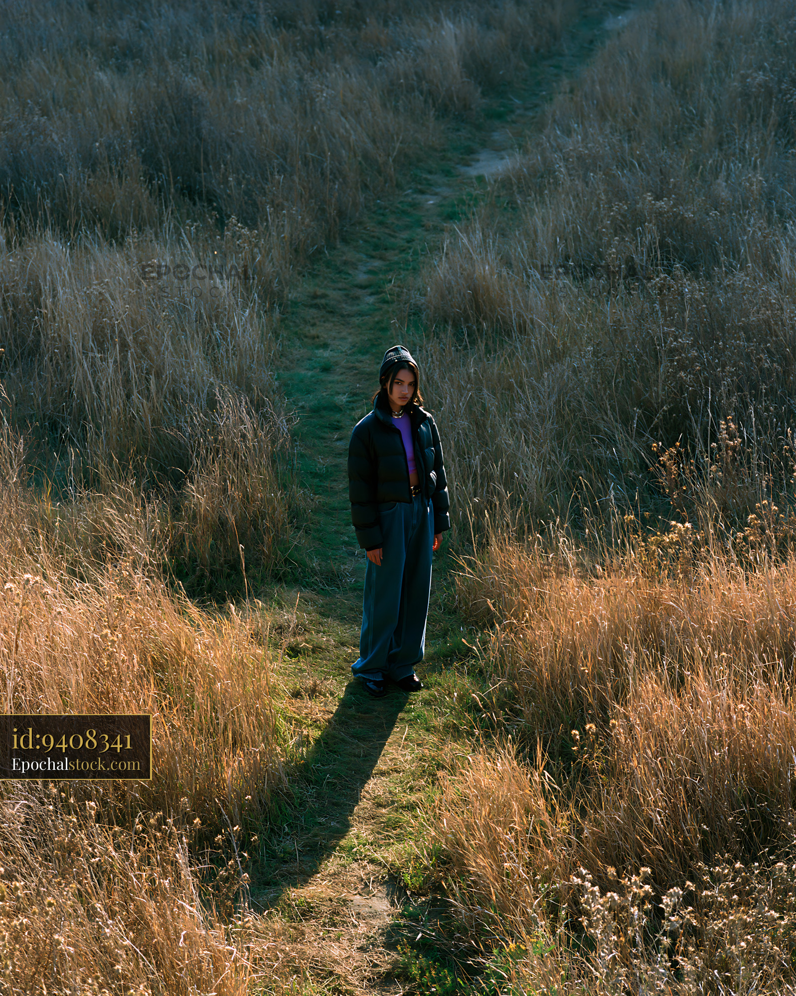 Watermarked full-resolution preview of Person standing in a grassy area with tall plants around