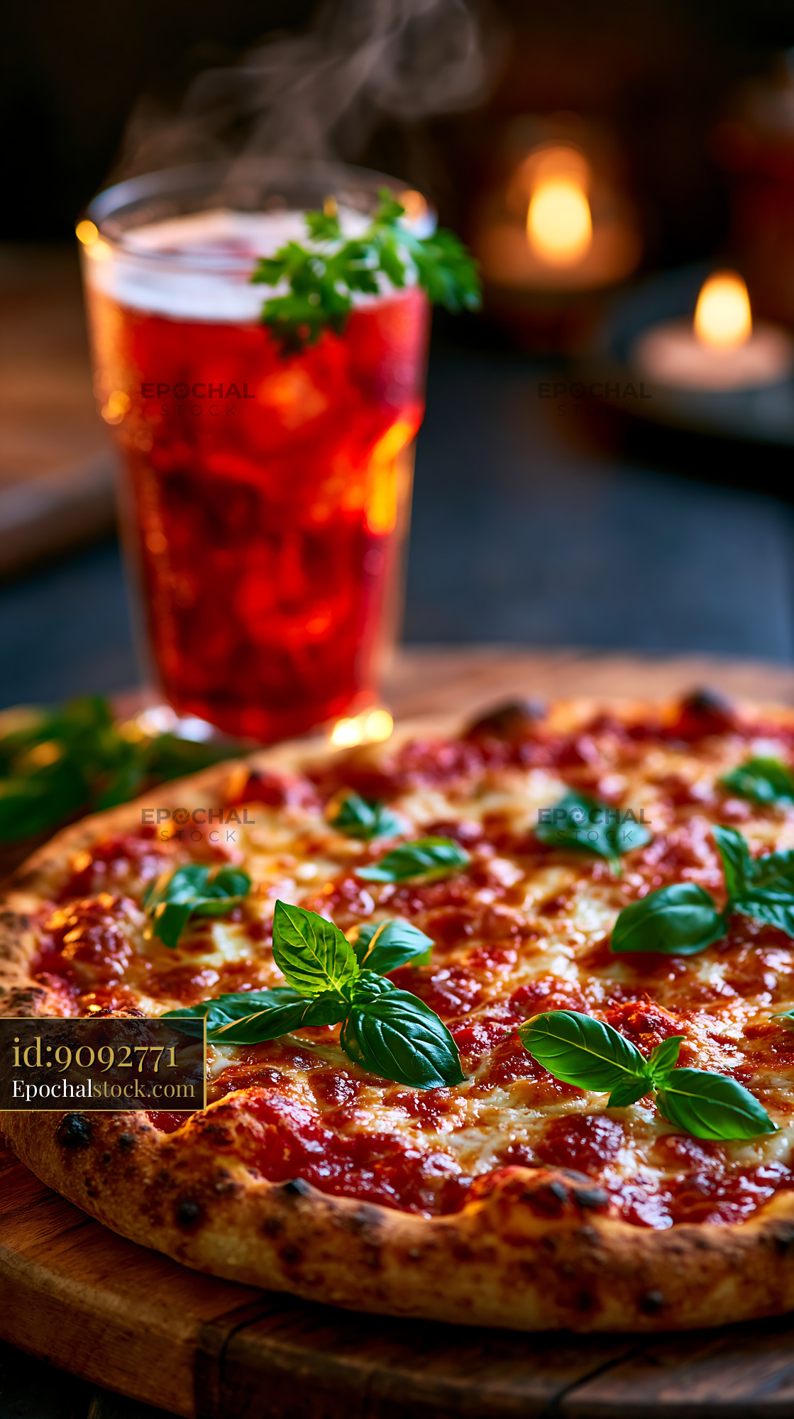 Watermarked full-resolution preview of Freshly baked pizza with basil and a drink on the table