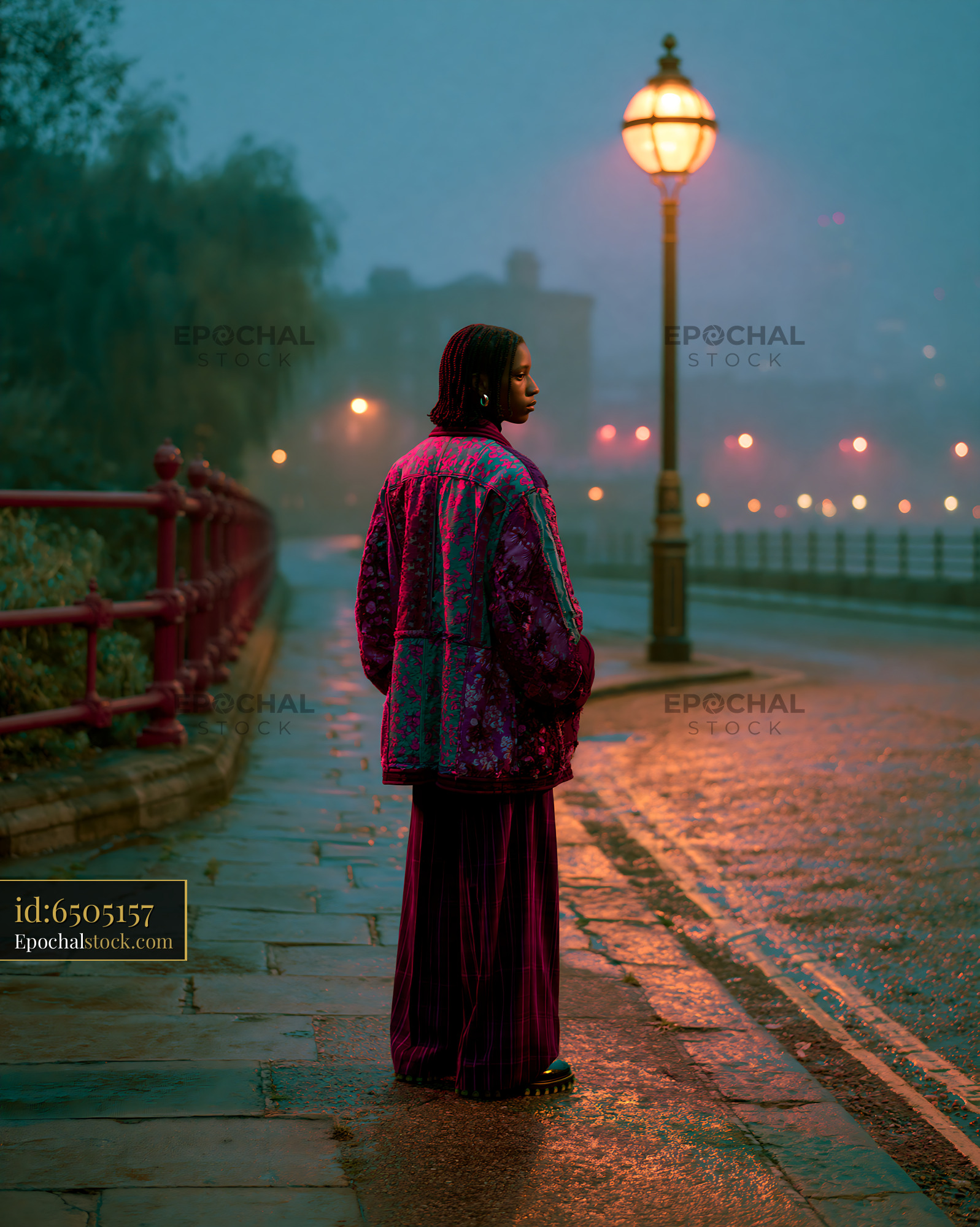 Watermarked full-resolution preview of Woman standing on a rainy street near a lamp post in the evening