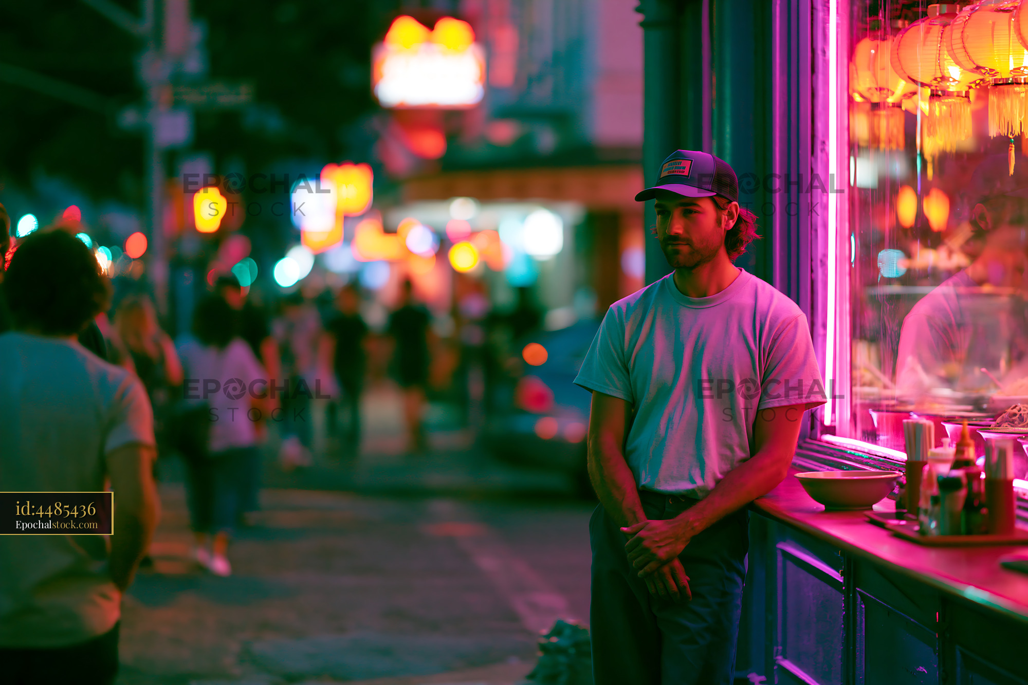 Watermarked full-resolution preview of Man standing by restaurant window at night with colorful lights