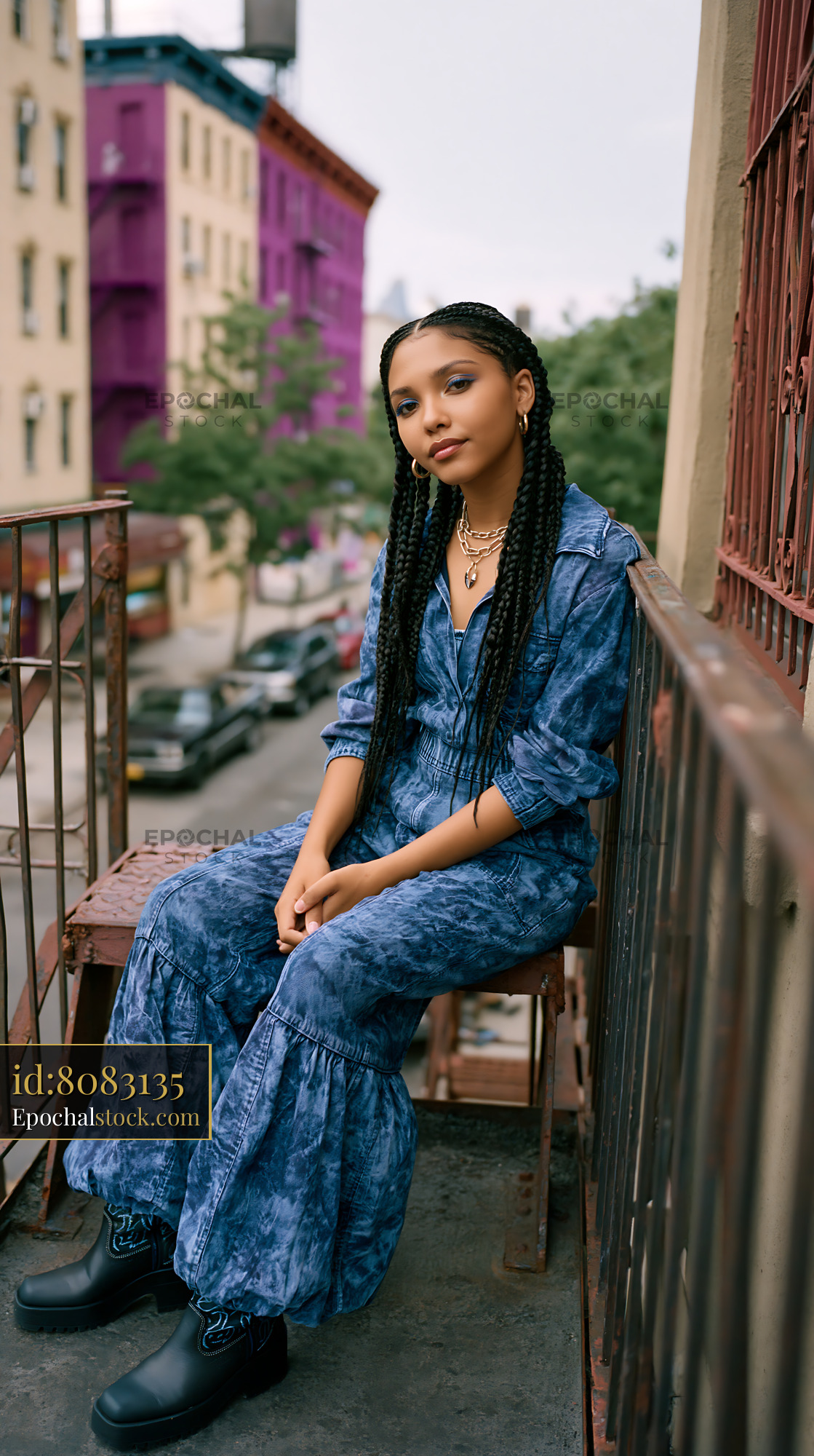 Watermarked full-resolution preview of Young person sitting on balcony in urban area