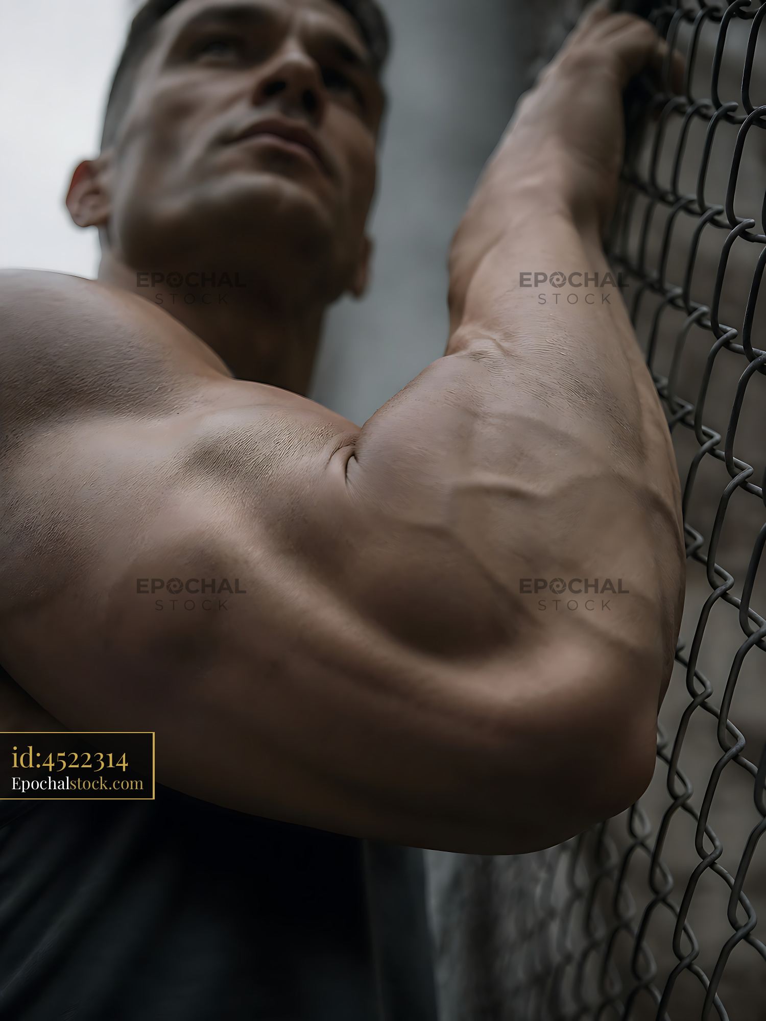 Watermarked full-resolution preview of Muscular man resting against a chain link fence