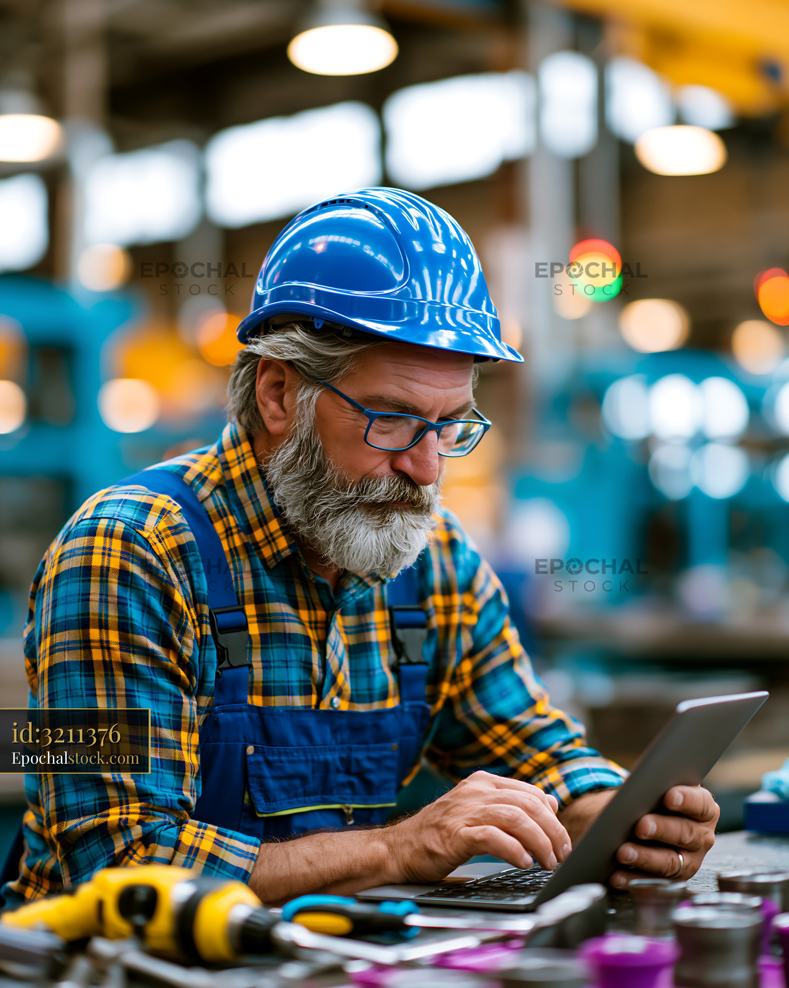 Watermarked full-resolution preview of Worker using laptop in industrial workshop