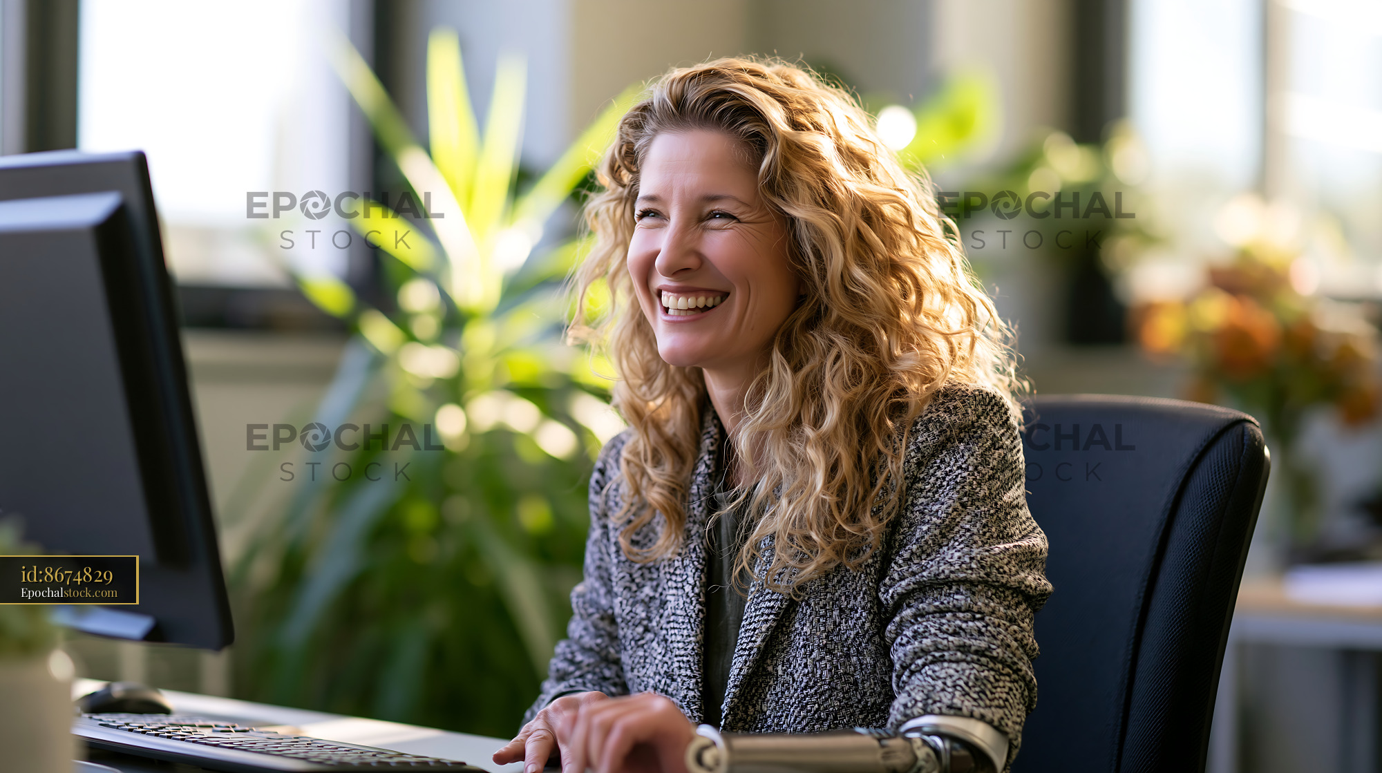 Watermarked full-resolution preview of Woman with curly hair working at a computer in an office setting