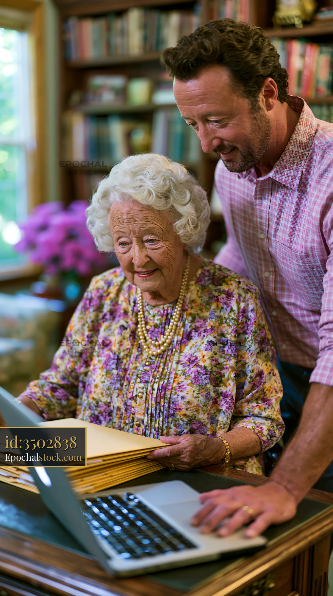 Watermarked full-resolution preview of Man helping elderly woman with laptop in cozy home setting