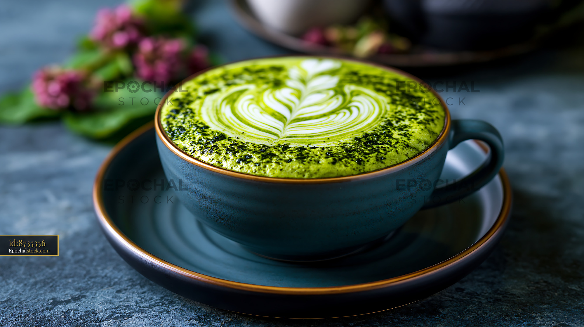 Watermarked full-resolution preview of Matcha latte with leaf design in blue cup on a gray surface