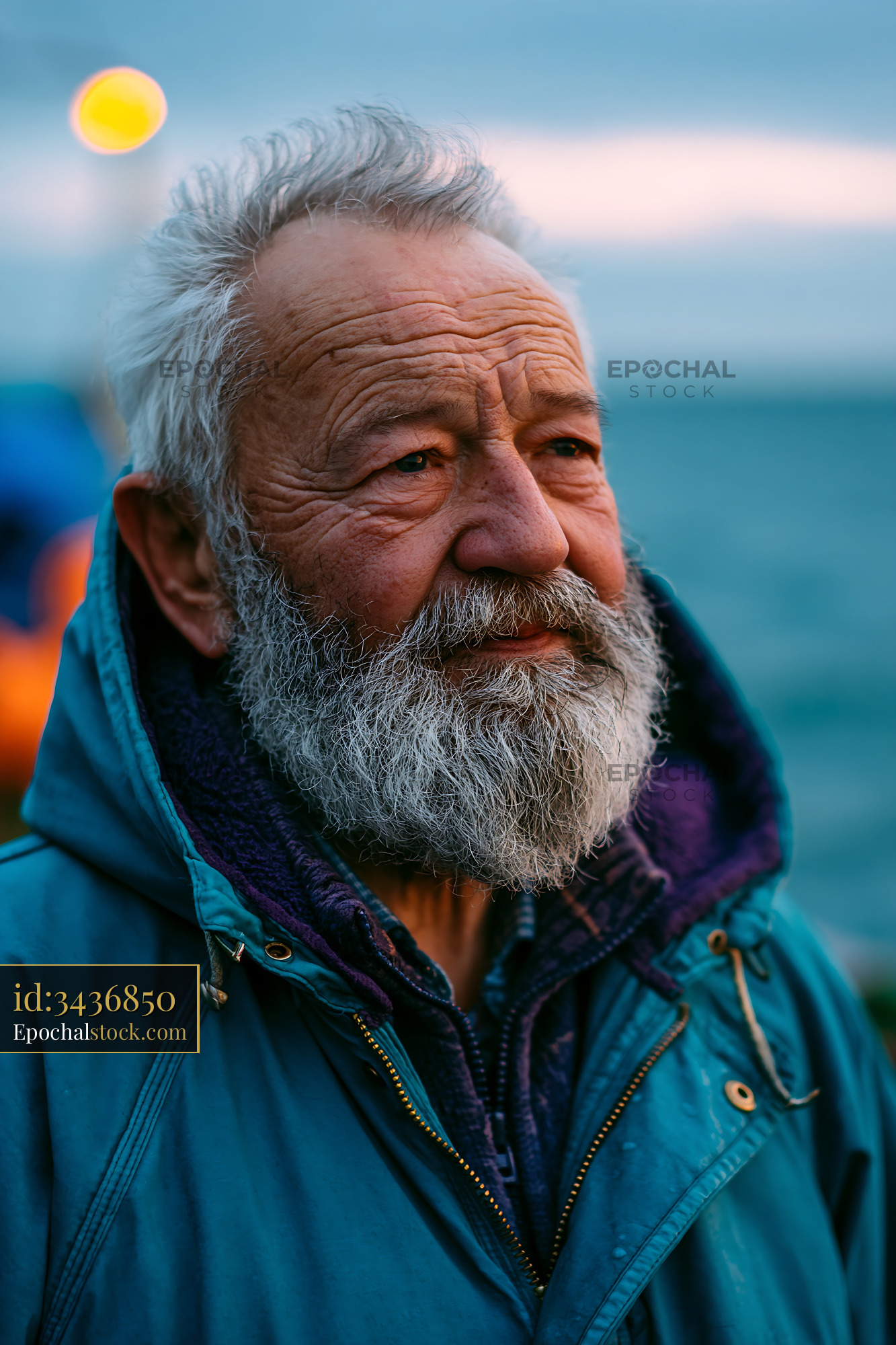 Watermarked full-resolution preview of Elderly man with beard standing near water at sunset