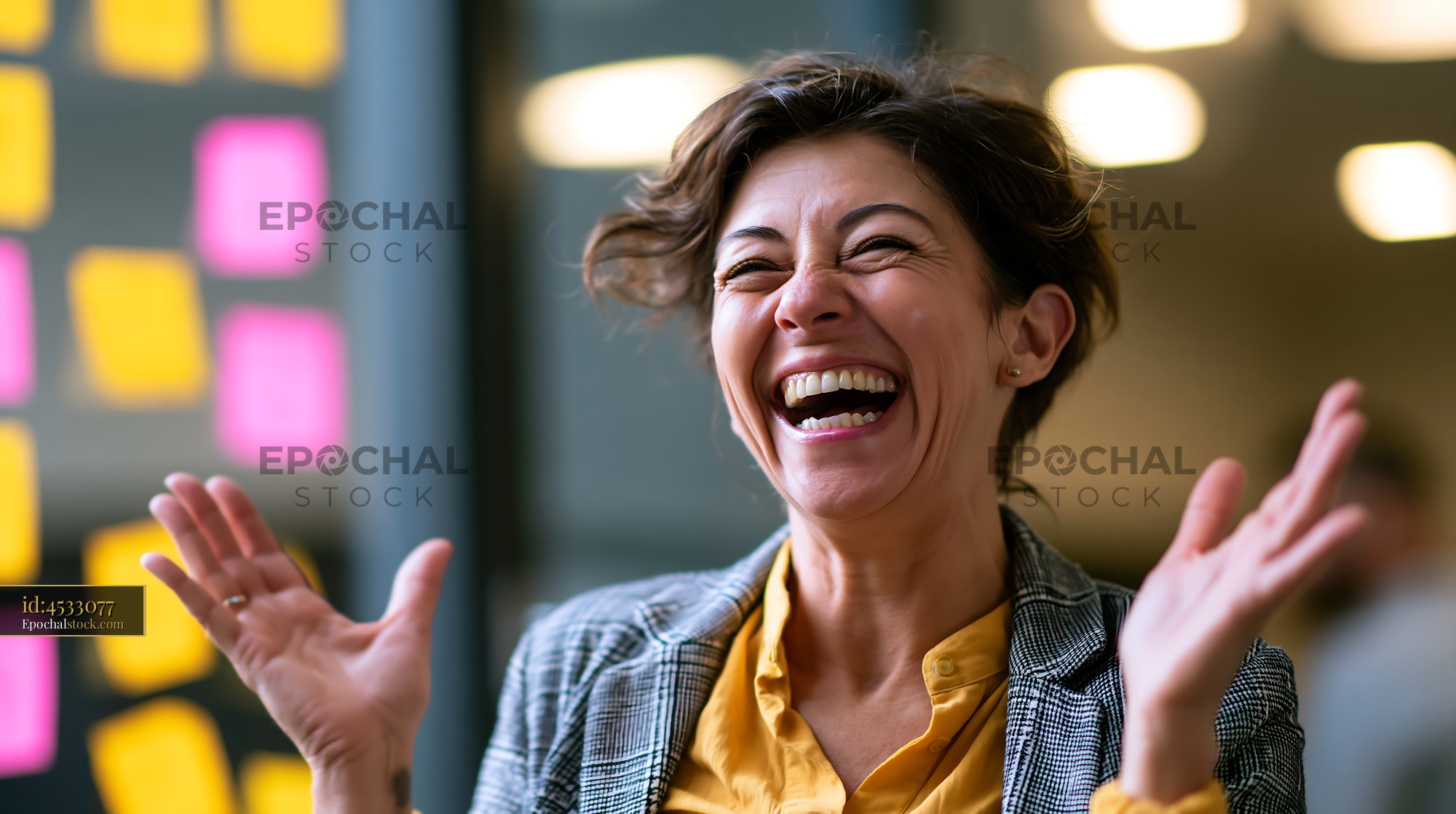 Watermarked full-resolution preview of Woman laughing with hands raised in a modern office space