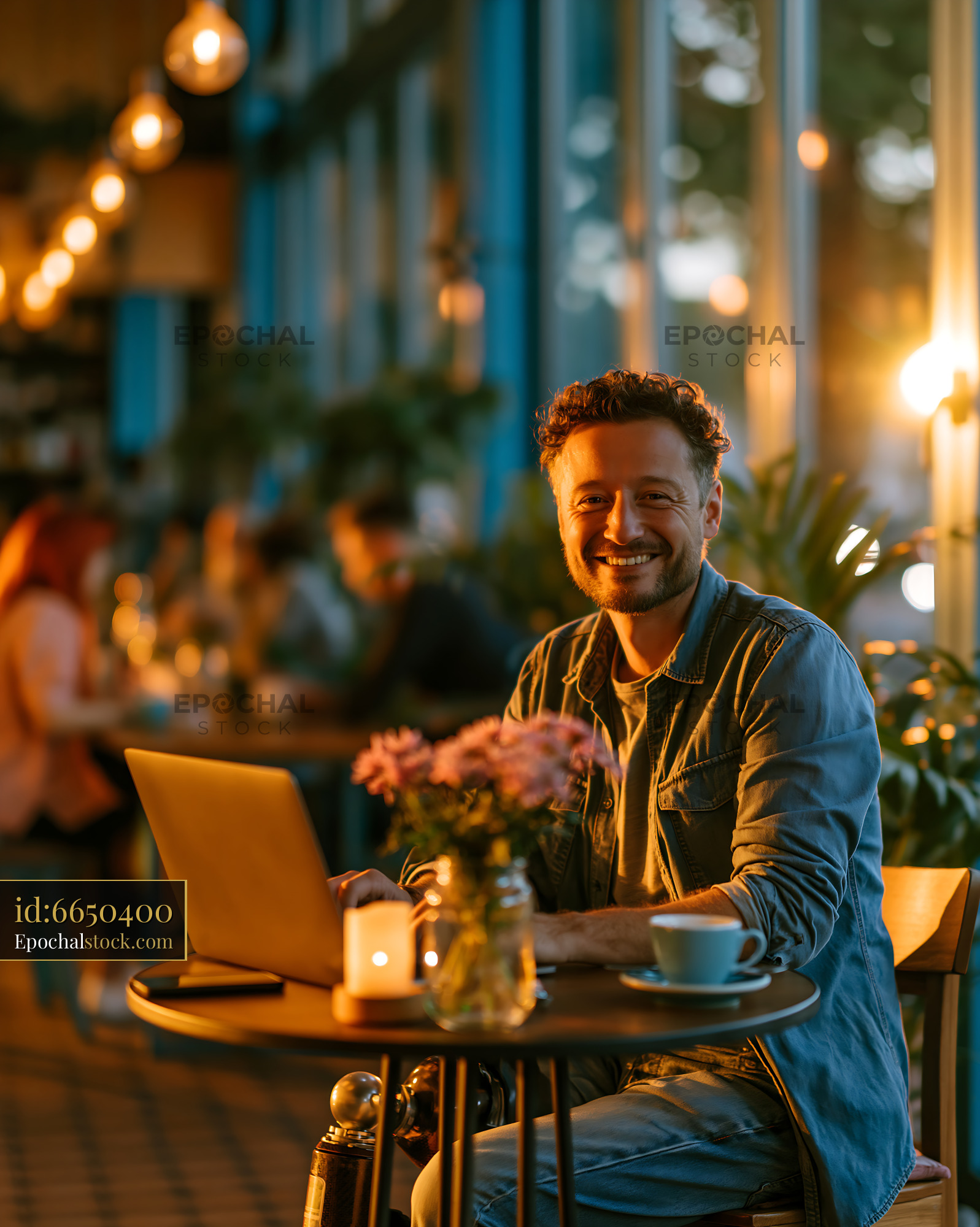 Watermarked full-resolution preview of Man working on laptop in cafe during evening with warm lighting