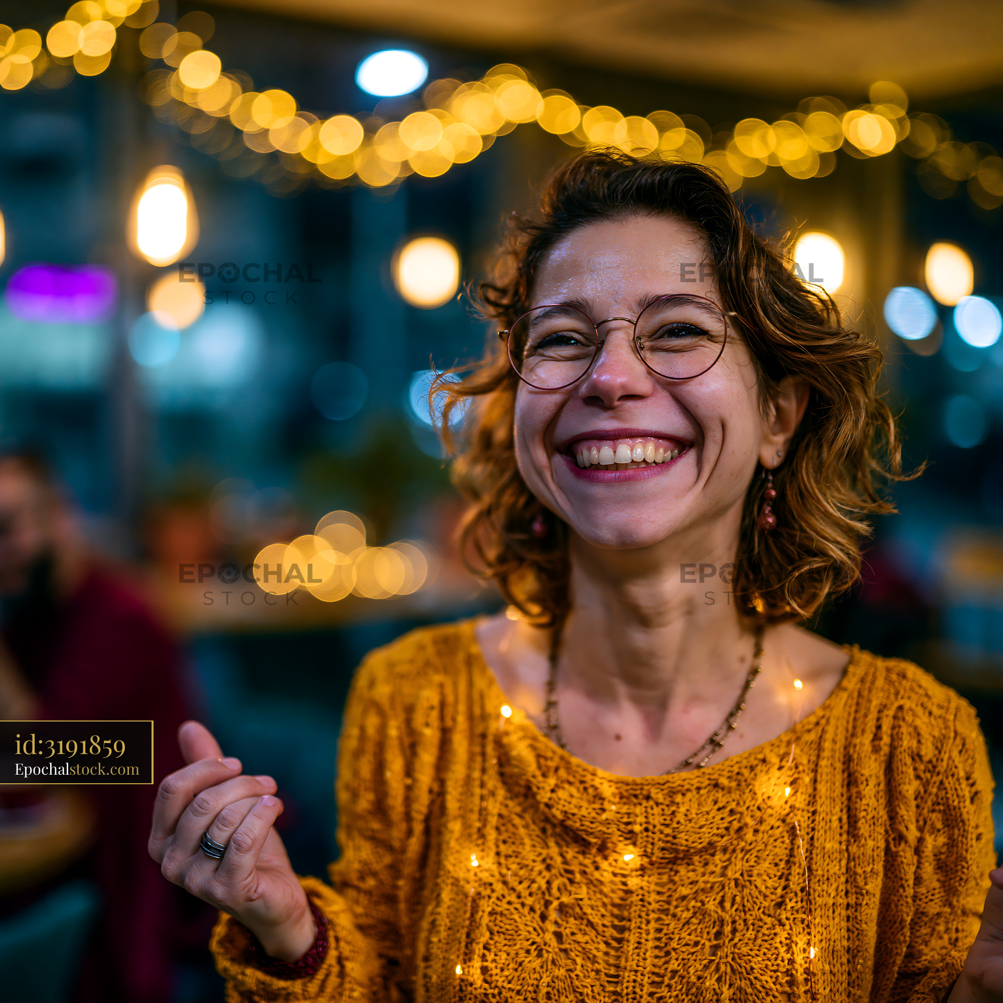 Watermarked full-resolution preview of Smiling woman with curly hair in a cafe at night