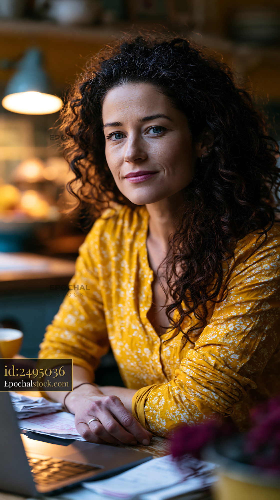 Watermarked full-resolution preview of Woman with curly hair sitting at a table in a cafe