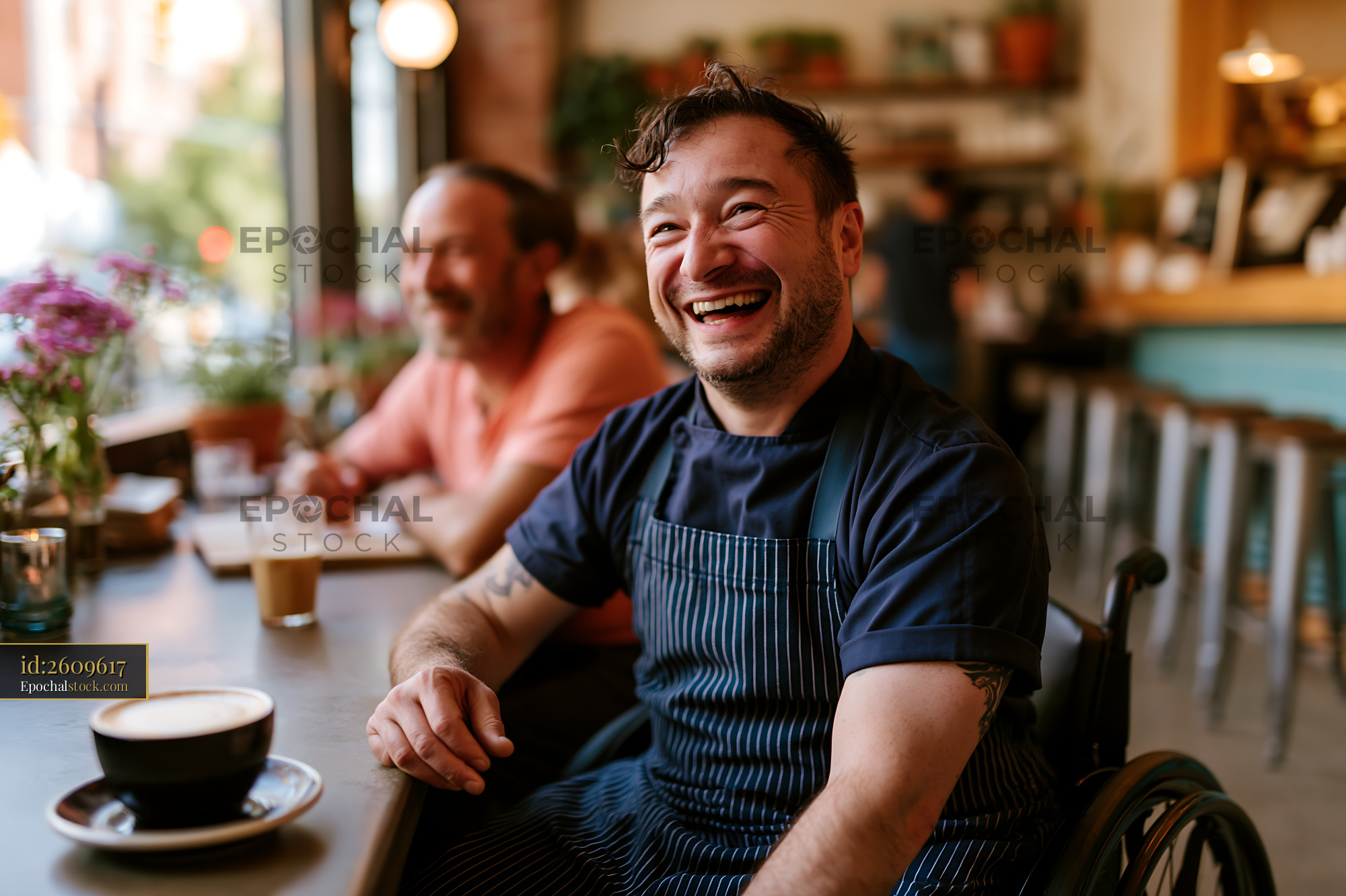 Watermarked full-resolution preview of Barista in wheelchair smiles while serving coffee in cafe