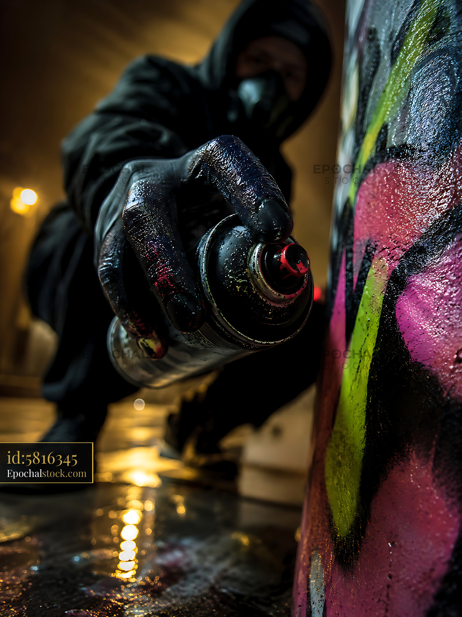 Watermarked full-resolution preview of Street artist spray painting on urban wall at night