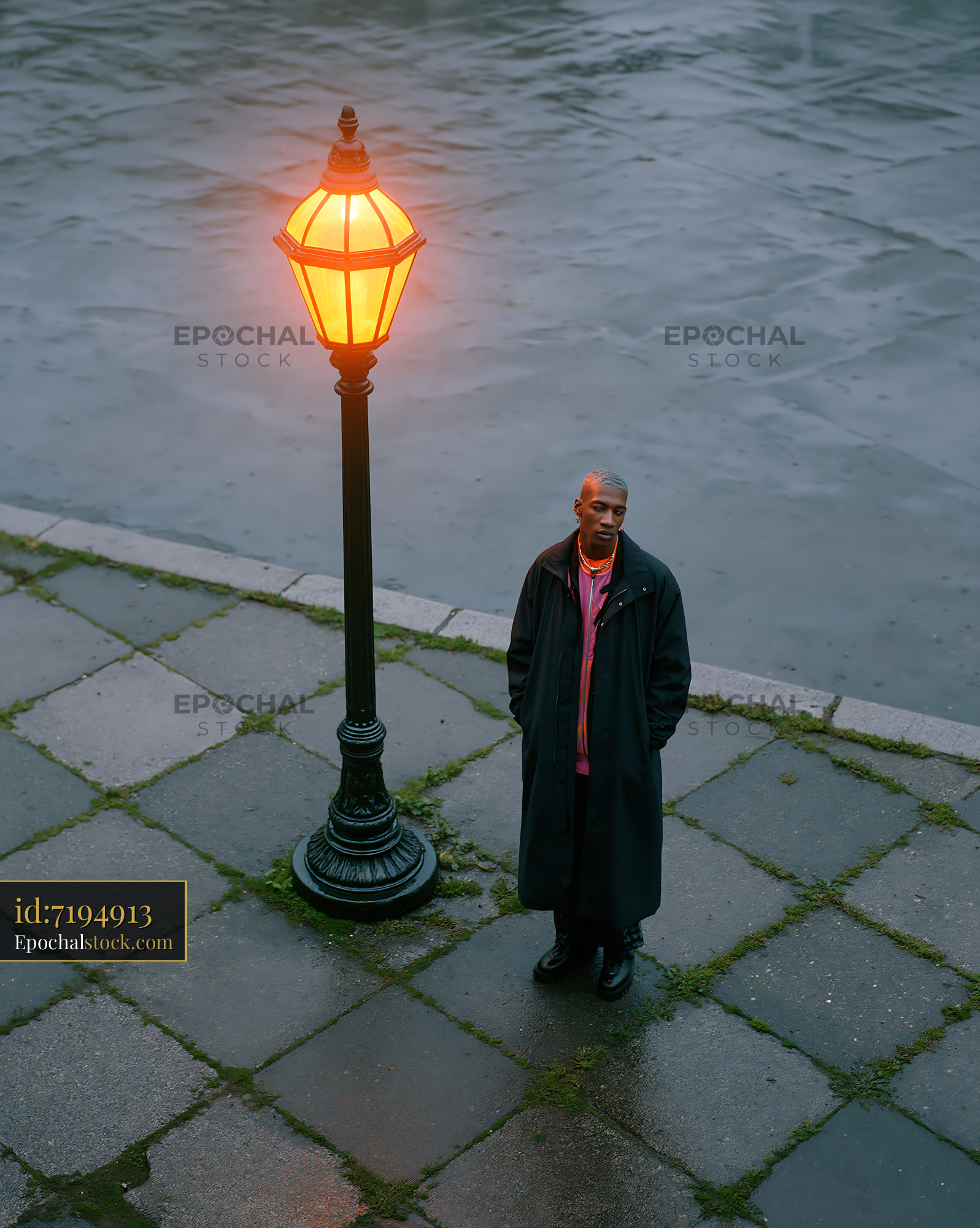 Watermarked full-resolution preview of Man standing near a street lamp on a rainy evening