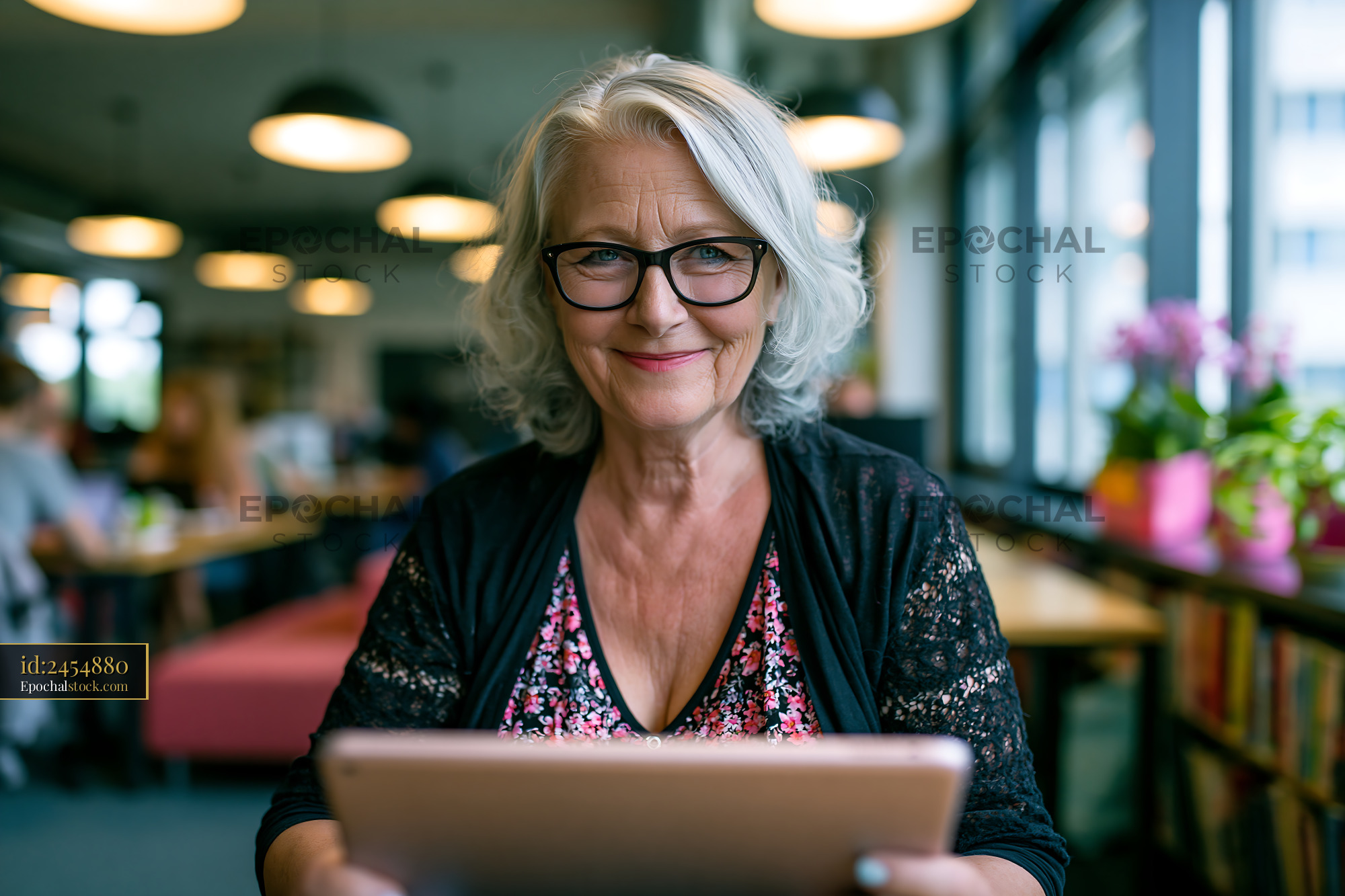 Watermarked full-resolution preview of Smiling older woman using a tablet in a cafe