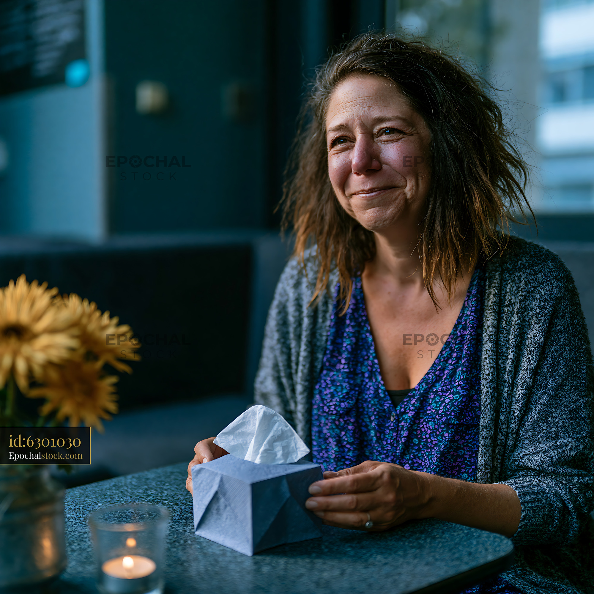 Watermarked full-resolution preview of Woman smiling while folding paper in a cafe