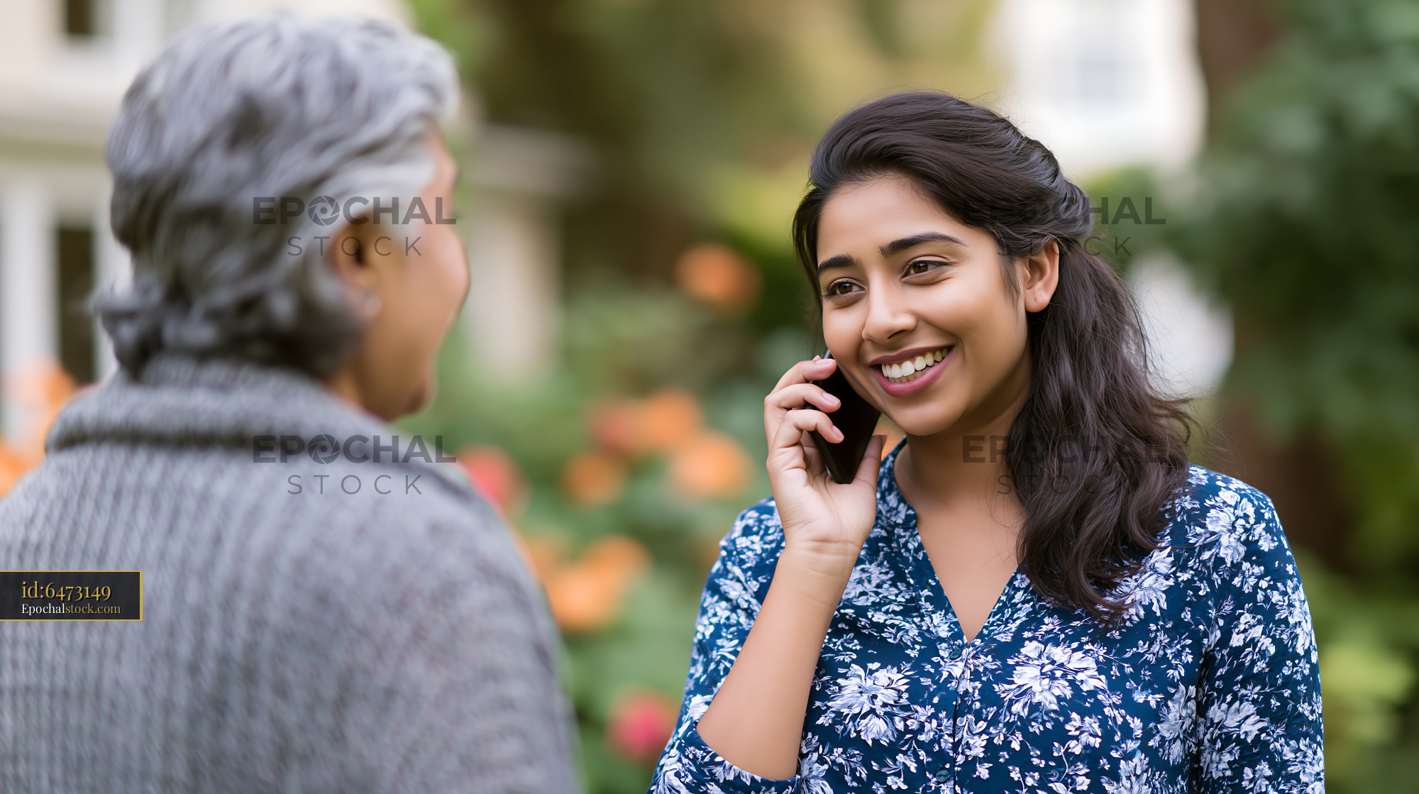 Watermarked full-resolution preview of Woman talking on the phone outdoors while smiling at another person