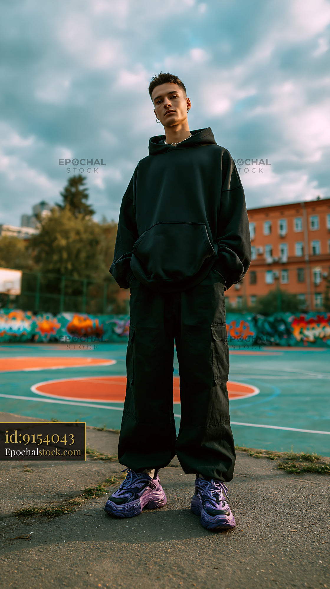 Watermarked full-resolution preview of Young man standing on basketball court with colorful graffiti