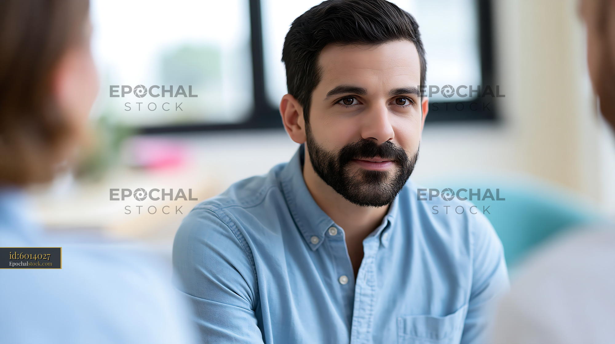 Watermarked full-resolution preview of Man engaging in conversation with two people in a bright room