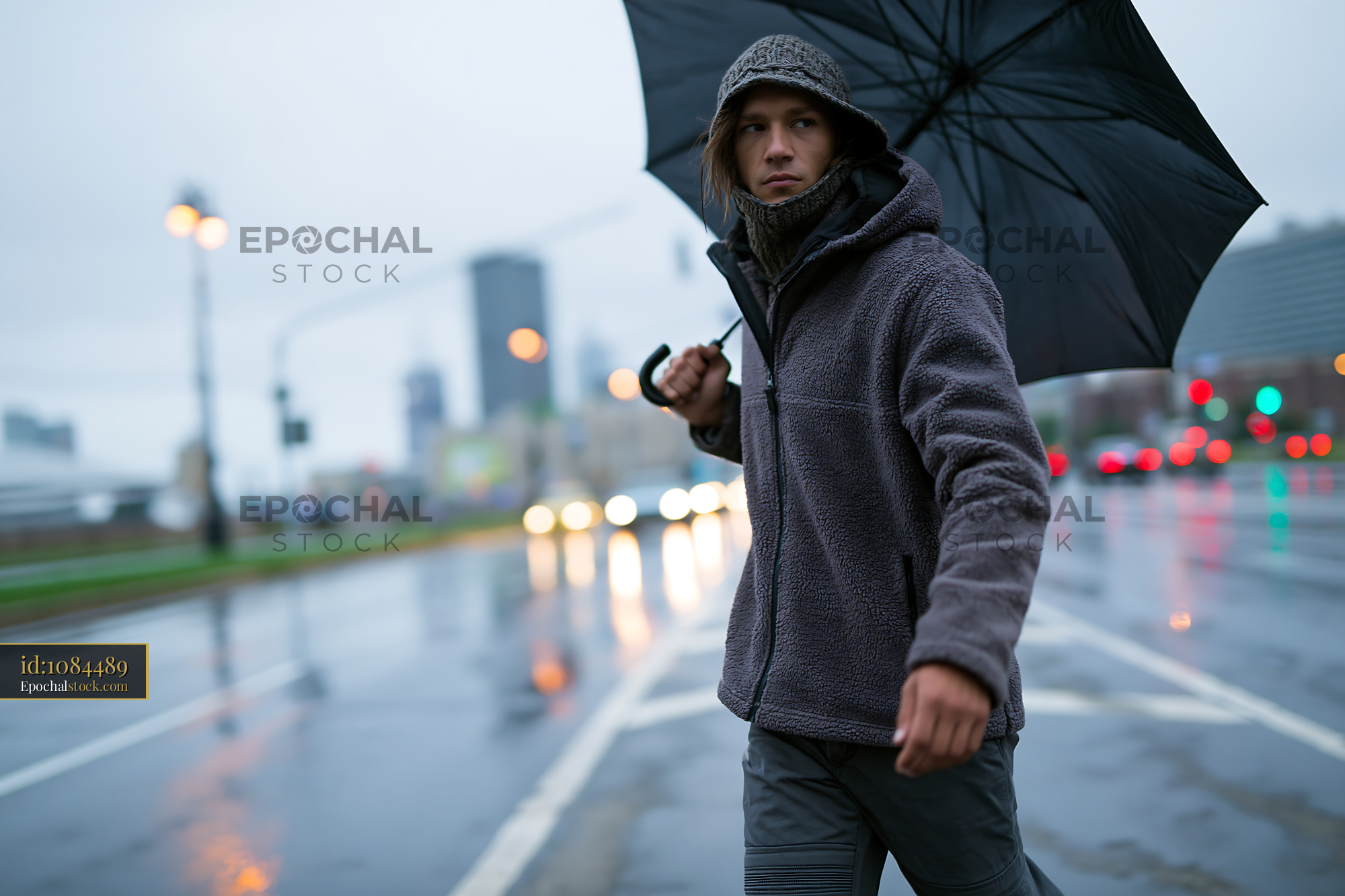 Watermarked full-resolution preview of Man walking on wet street holding umbrella in rainy weather