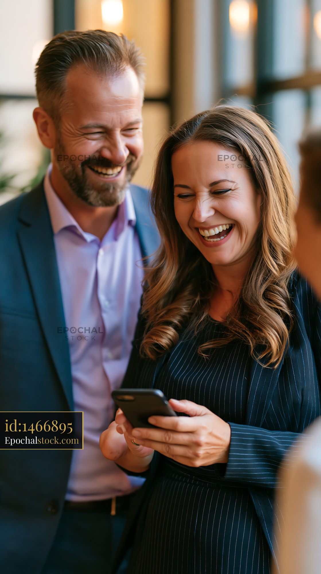 Watermarked full-resolution preview of Business colleagues sharing a laugh while looking at a phone