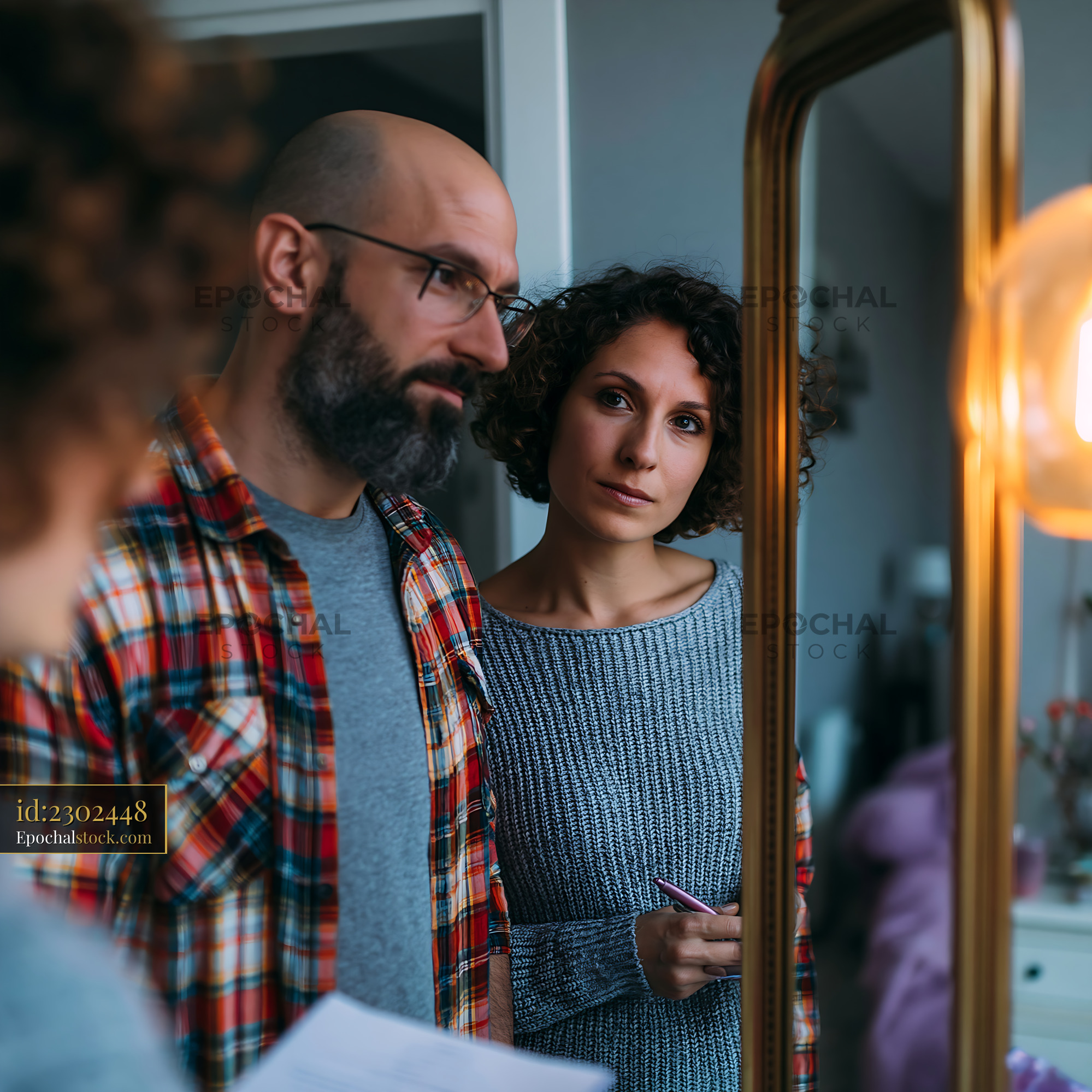 Watermarked full-resolution preview of Couple looking at a mirror while discussing plans