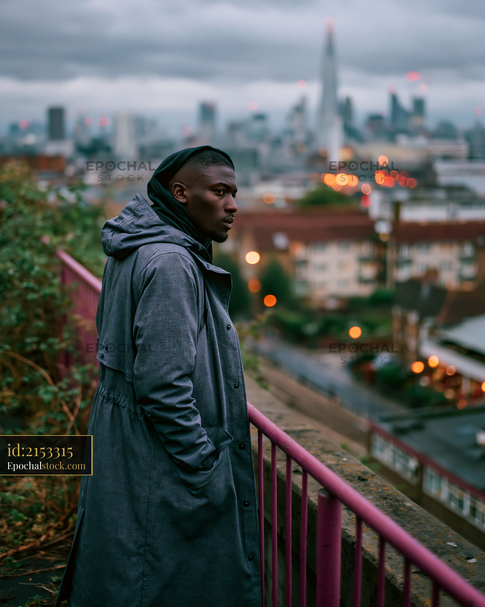 Watermarked full-resolution preview of Man in gray coat looking over city skyline at dusk