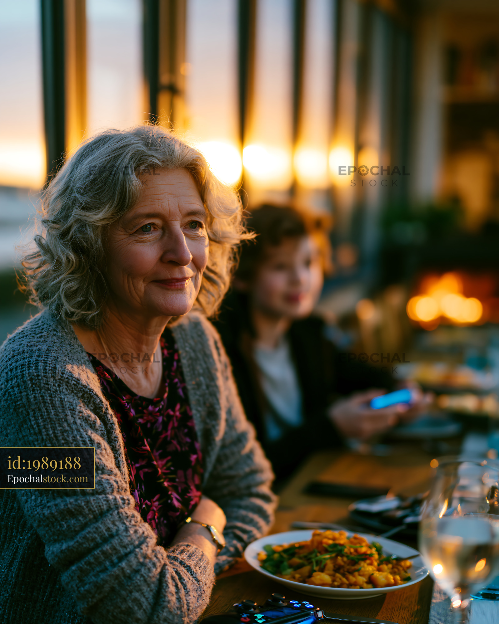 Watermarked full-resolution preview of Mature woman enjoying an evening meal in warm restaurant light
