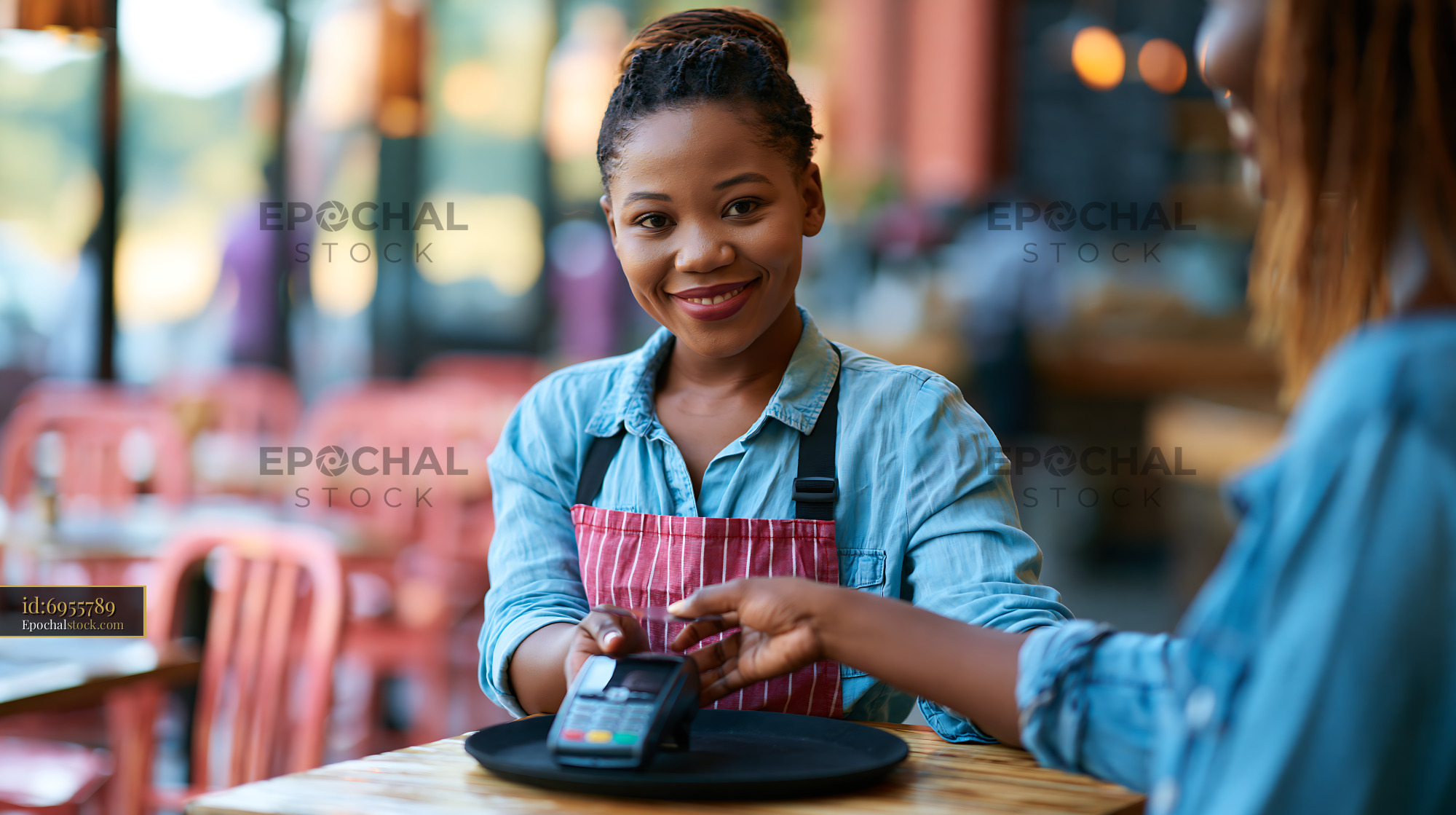 Watermarked full-resolution preview of Server assisting customer with payment at a cafe table