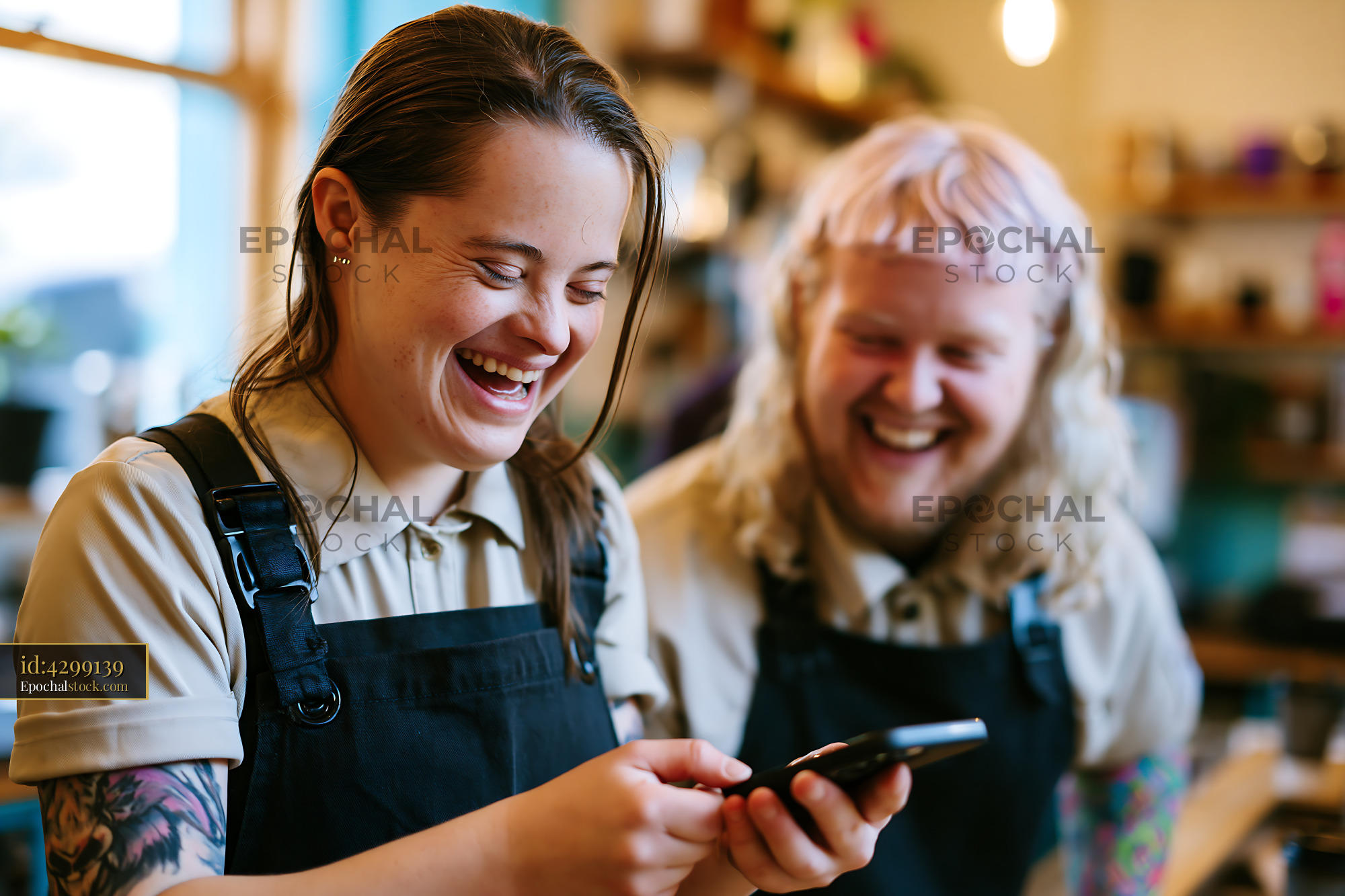 Watermarked full-resolution preview of People laughing while using a smartphone in a cafe setting