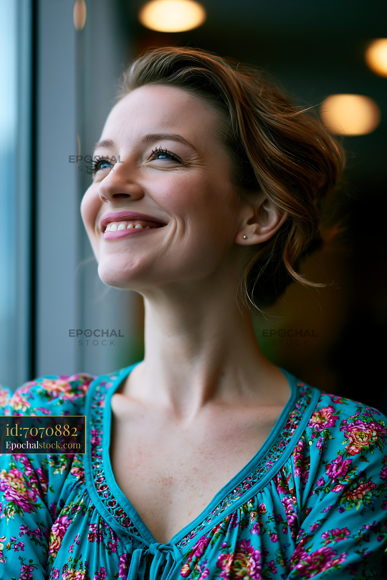 Watermarked full-resolution preview of Woman smiling by window with soft lighting