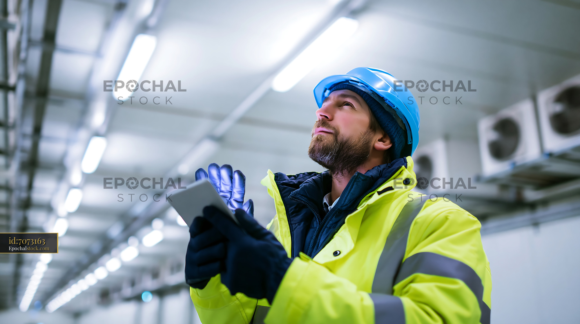 Watermarked full-resolution preview of Construction worker checking equipment in industrial setting