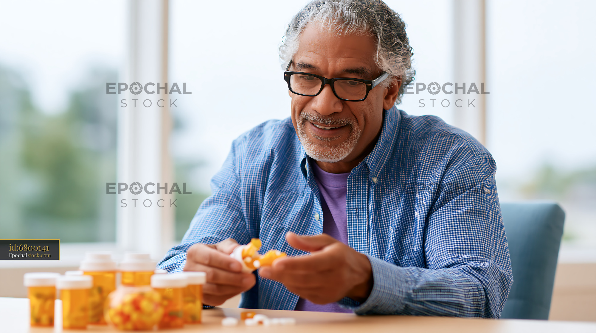 Watermarked full-resolution preview of Elderly man organizing medication in a bright indoor space