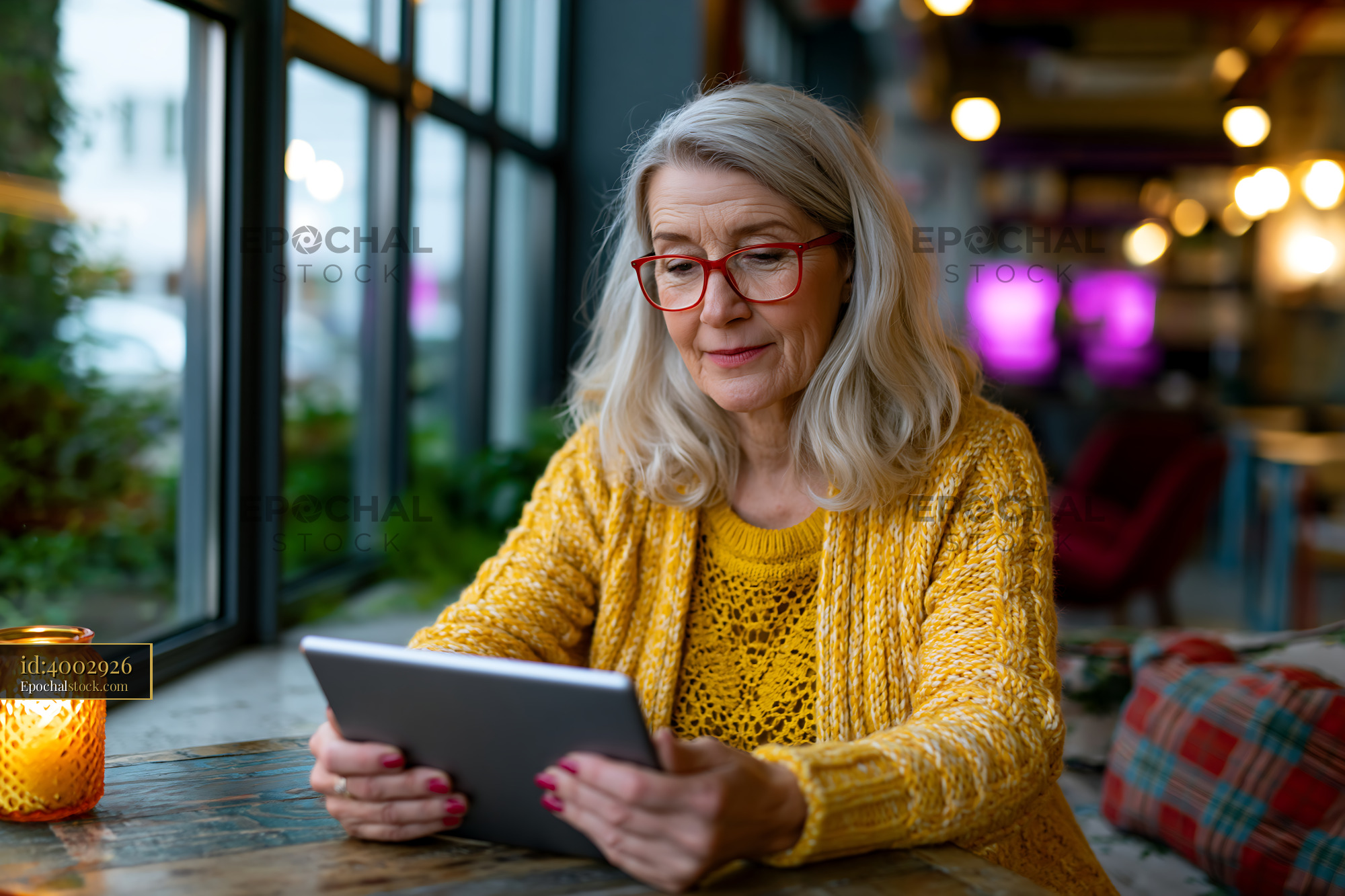 Watermarked full-resolution preview of Senior woman using a tablet in a cozy cafe setting