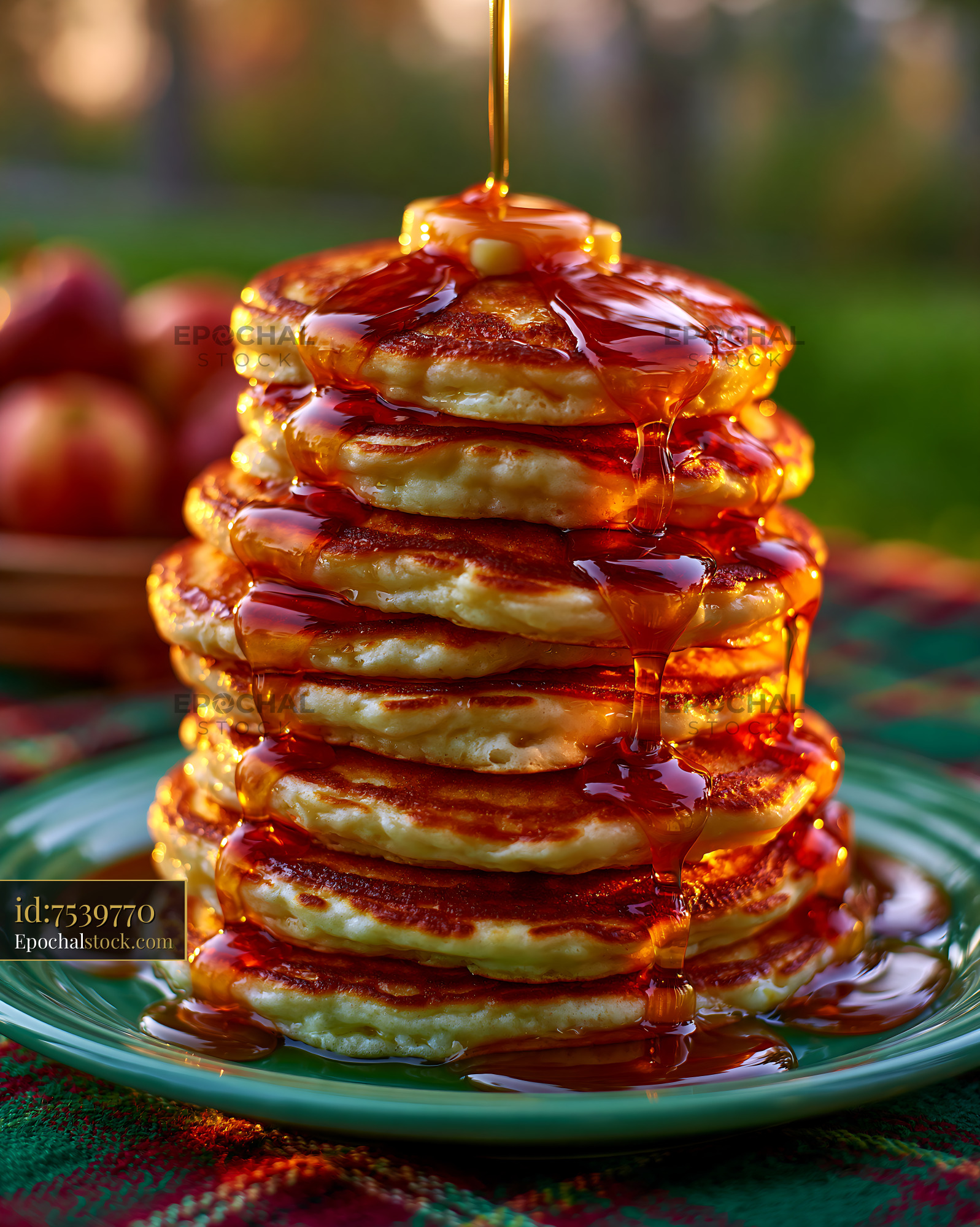 Watermarked full-resolution preview of Stack of pancakes with syrup and butter served outdoors
